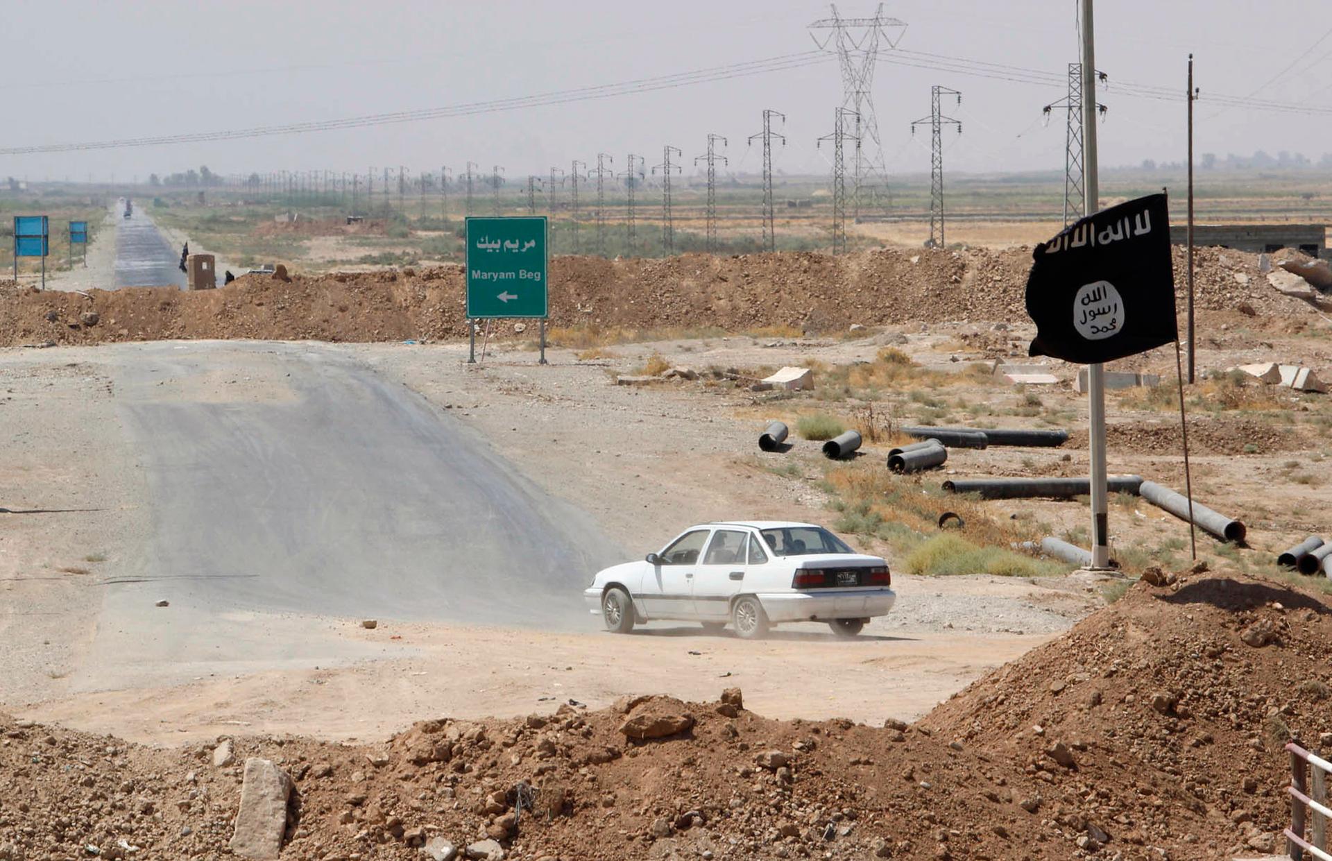 A car drives near a flag belonging to Islamic State militants at the end of a bridge in southern Kirkuk.