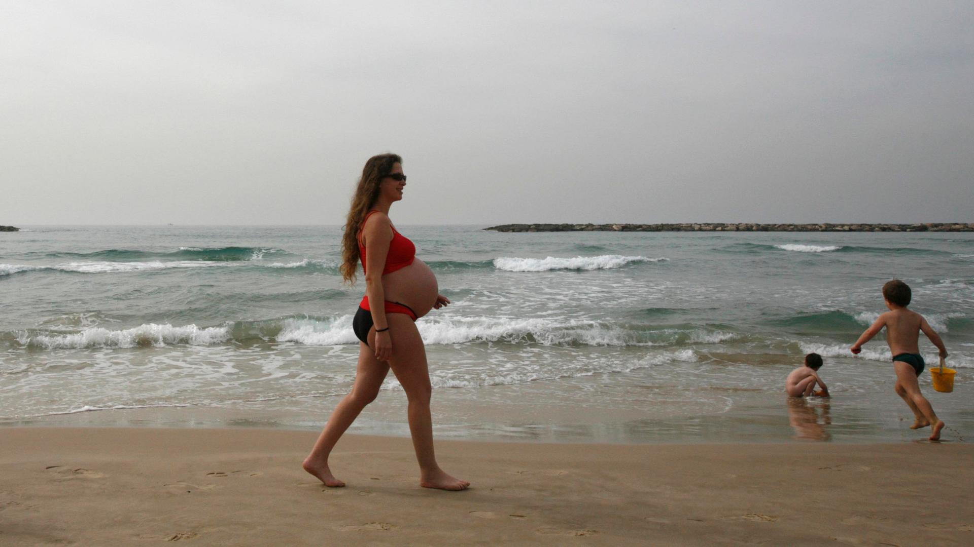 A woman walks on the shore of the Mediterranean in Tel Aviv.