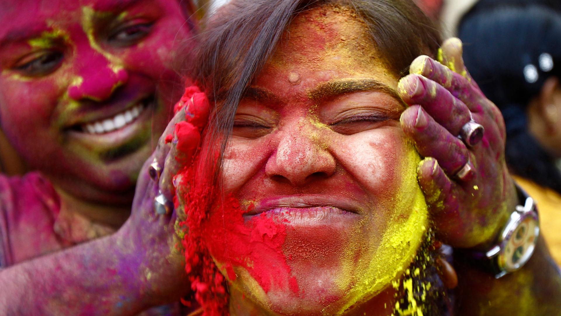 A student of Rabindra Bharati University reacts as her fellow student applies colored powder on her face during celebrations for Holi in Kolkata.