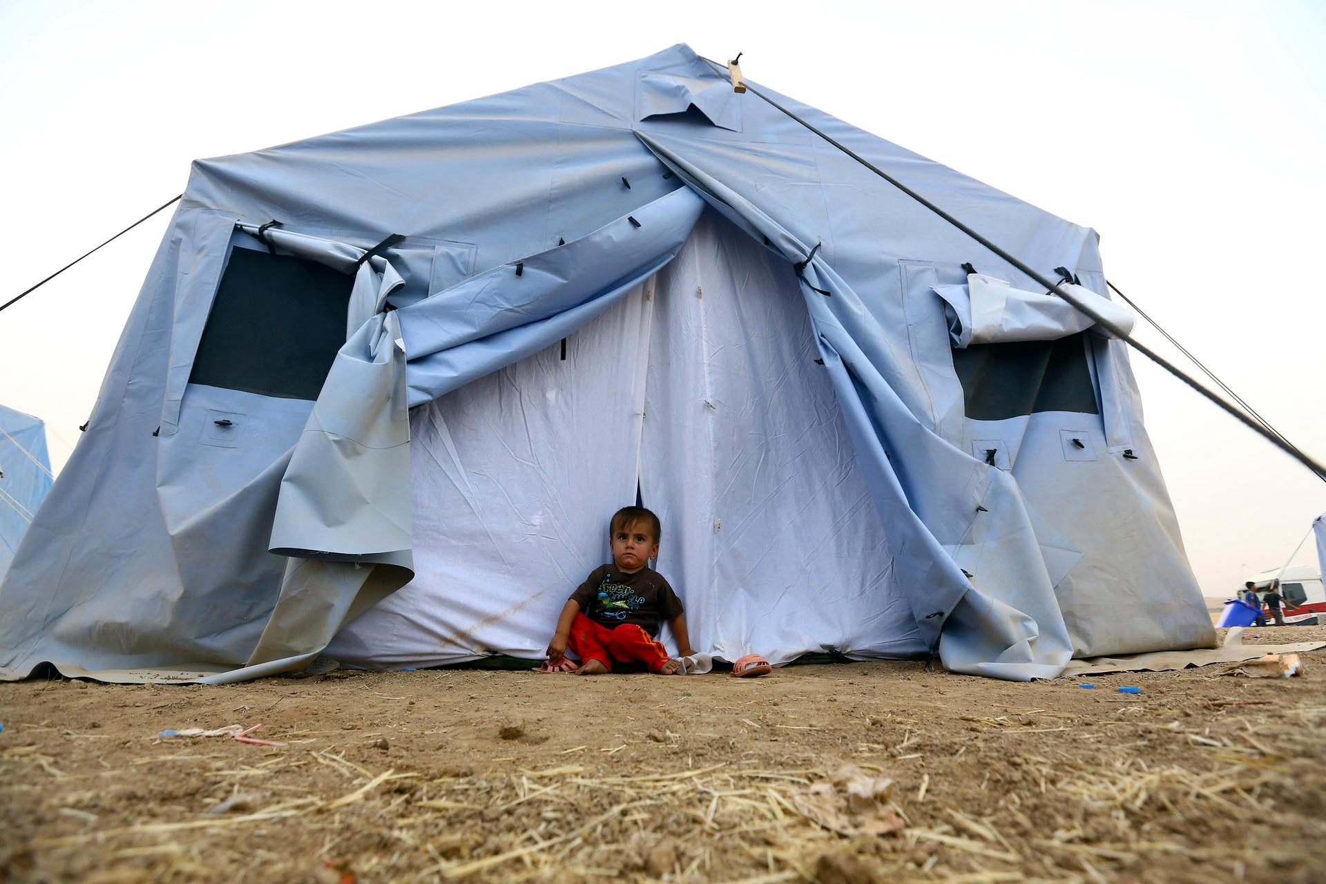 A boy who fled from the violence in Mosul sits outside a tent at a camp on the outskirts of Erbil in Iraq's Kurdistan region.