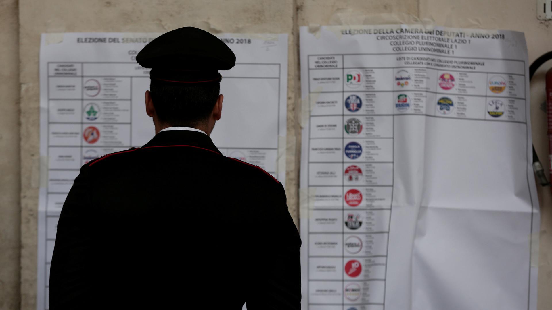 An Italian policeman looks at an electoral poster at a polling station in Rome, March 4, 2018.