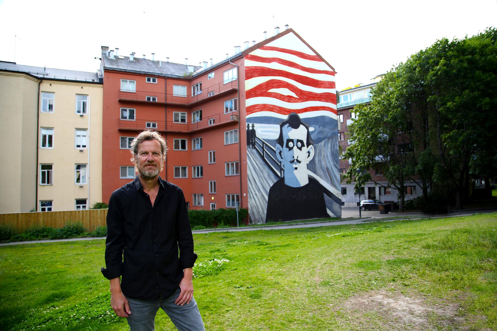 Steffen Kverneland stands in front of a large mural in the Tøyen neighborhood of a Oslo created from the cover of his graphic biography of Edvard Munch. The mural was created by Knverneland and another Norwegian, Monica Tollnes.