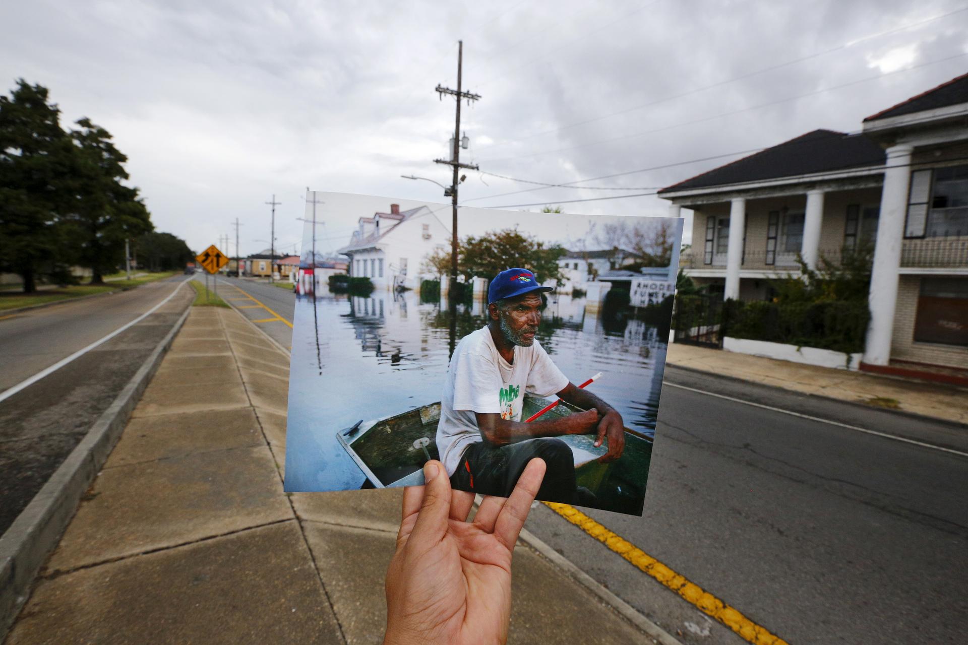 Photographer Carlos Barria holds a print of a photograph he took in 2005, as he matches it up at the same location 10 years on, in New Orleans. The print shows Errol Morning sitting on his boat on a flooded street September 5, 2005, after Hurricane Katrin