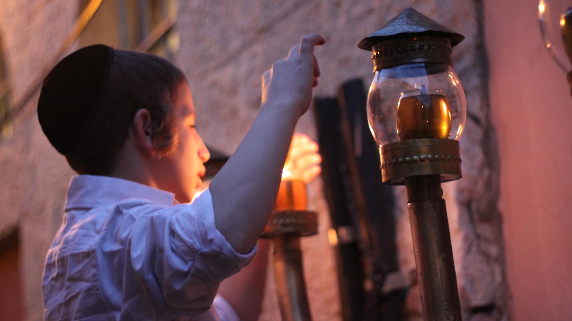 A young boy lights Hanukkah lights in Jerusalem's Nachlaot neighborhood.