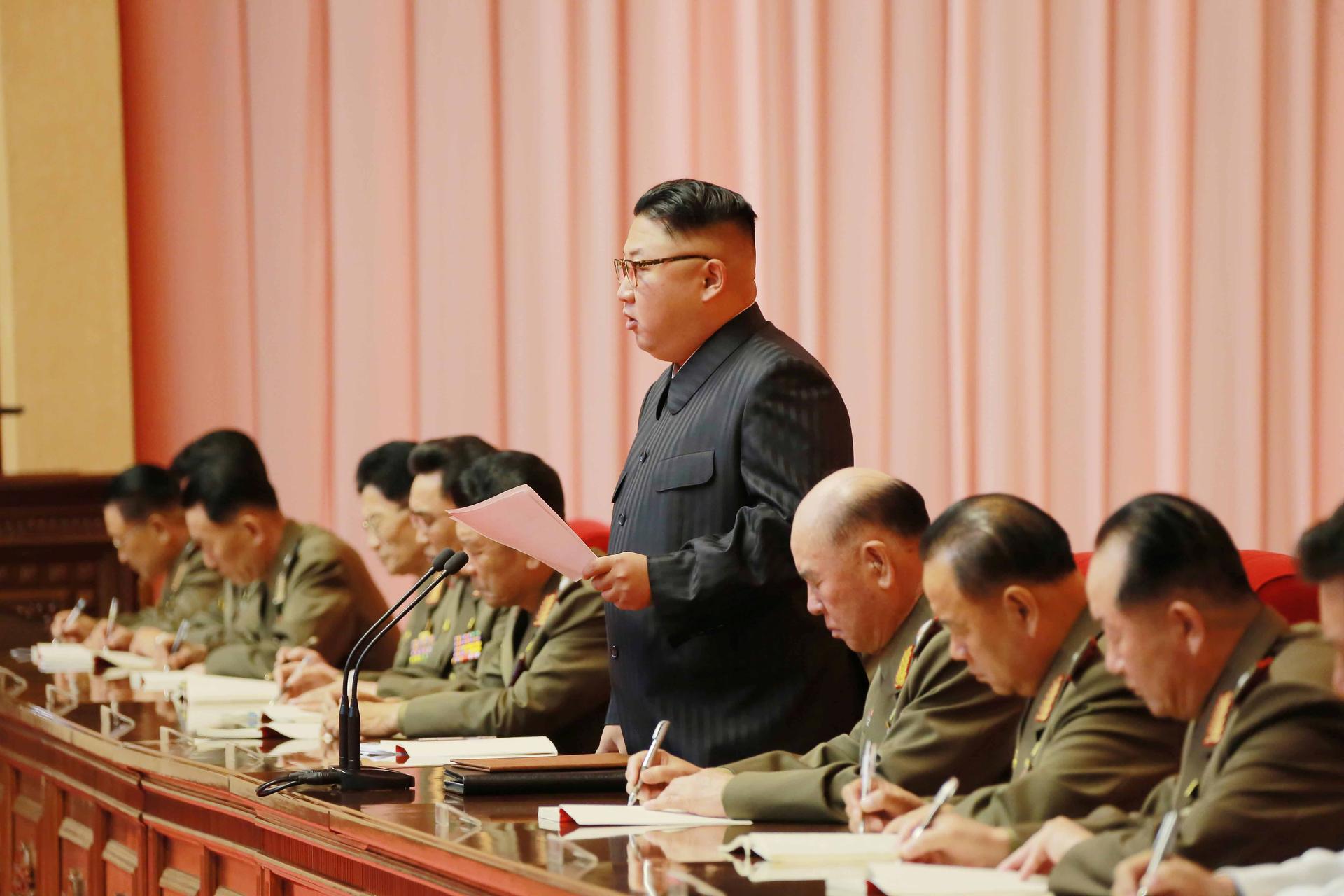 North Korean leader Kim Jong-un stands at a table in the middle of several military members .