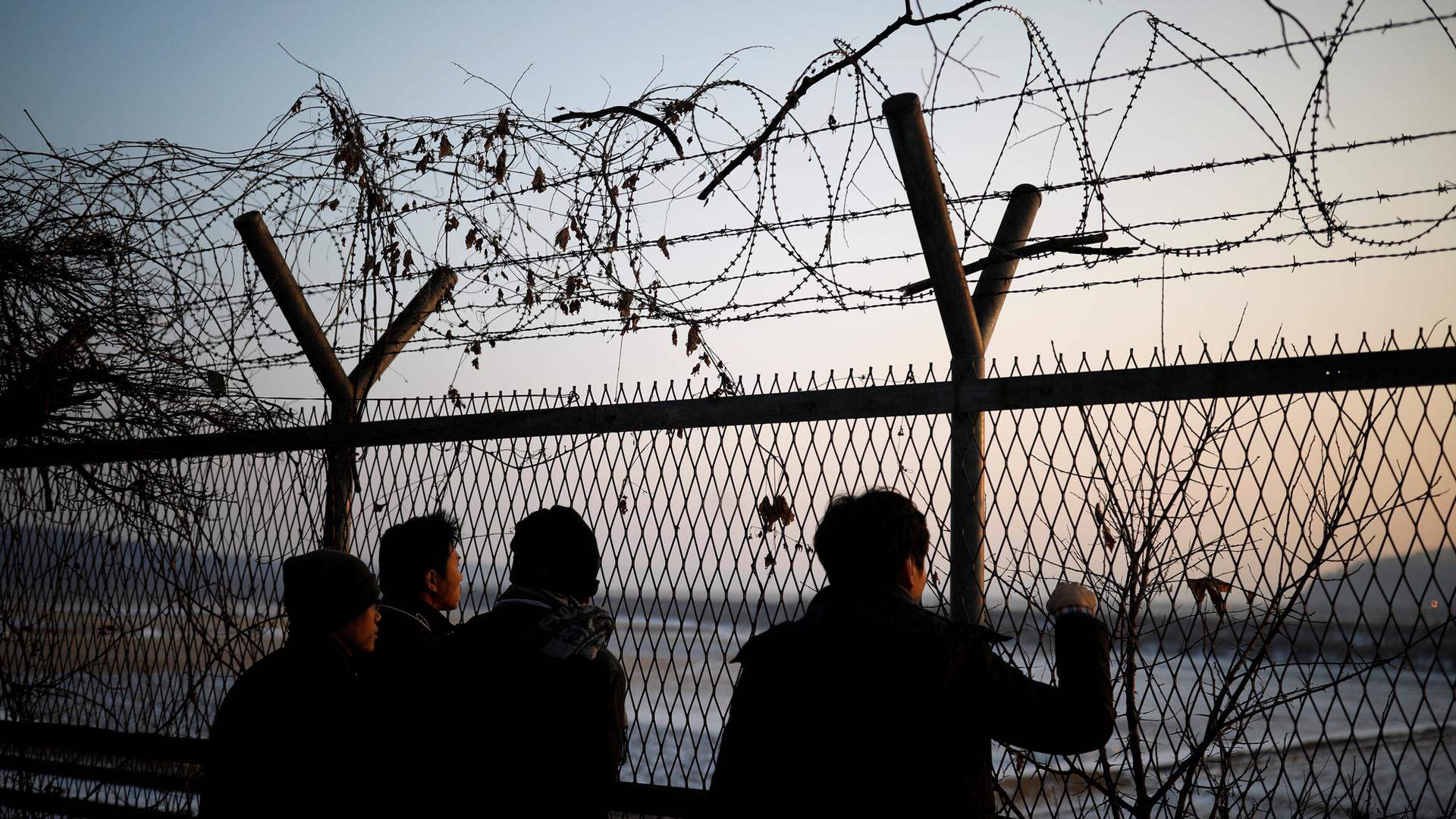 People look toward the north through a barbed-wire fence near the demilitarized zone separating the two Koreas, in Paju, South Korea.