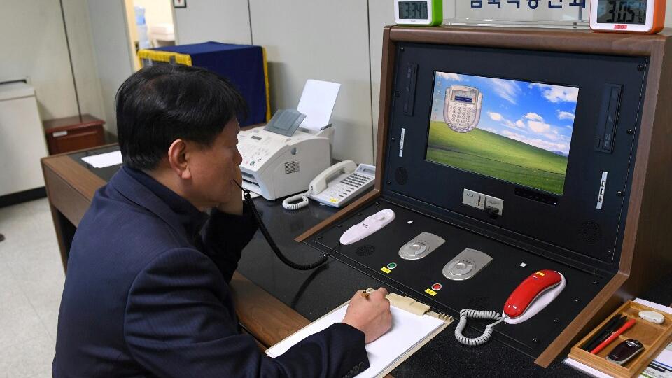 A South Korean government official sits at a terminal that has a red and green phone.