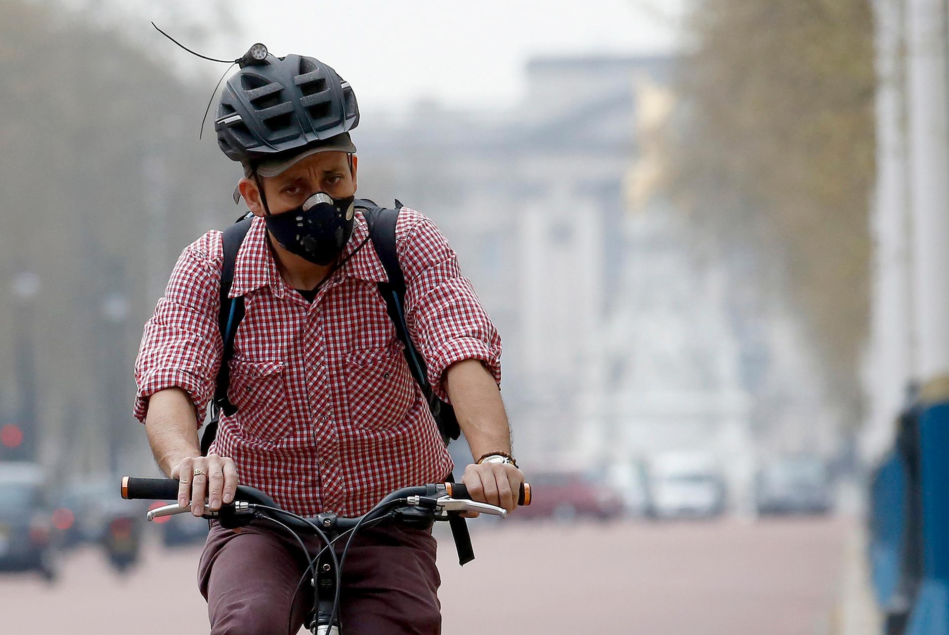 A cyclist wears a mask as he cycles near Buckingham Palace in London April 2, 2014. Britain's Meteorological Office forecast that London would be affected by smog this week, caused by powerful dust storms and strong winds in the Sahara.