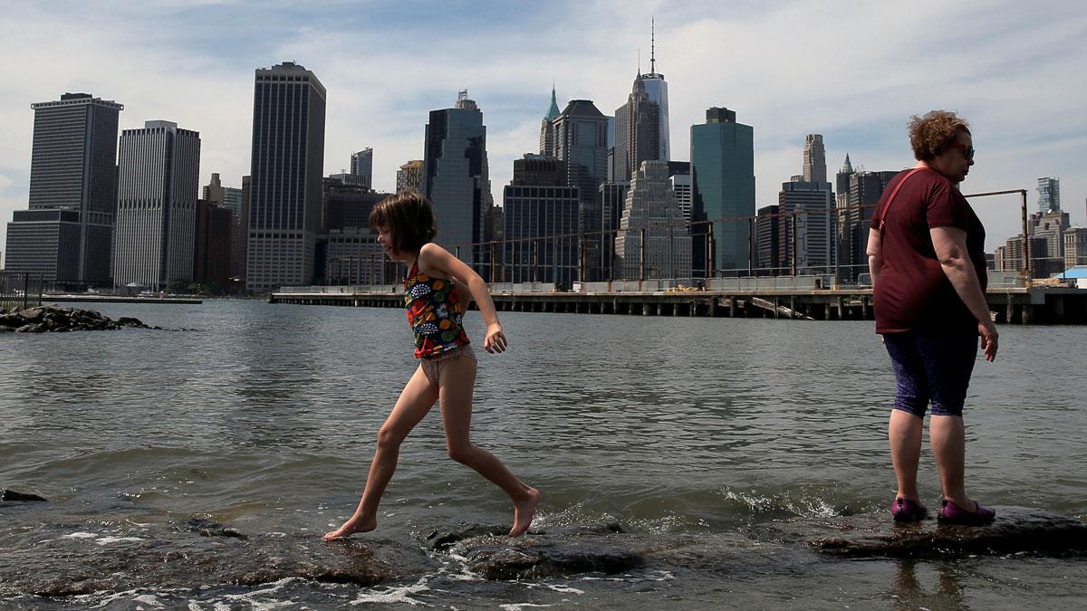 A young girl runs on the rocks under the skyline of lower Manhattan in Brooklyn Bridge Park. The South Street Seaport area, on Manhattan's Lower East Side, saw some of the worst flooding during Superstorm Sandy.