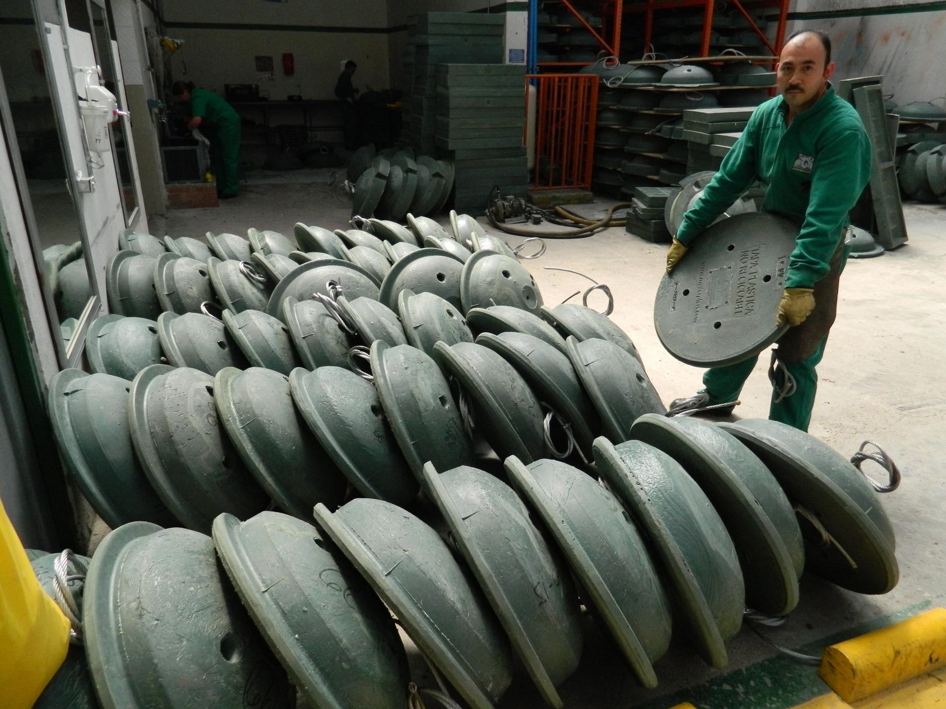 A worker at Maderplast in Bogota stacks plastic manhole covers.  They're designed to replace the thousands of metal covers that thieves have been stealing to sell as scrap metal.