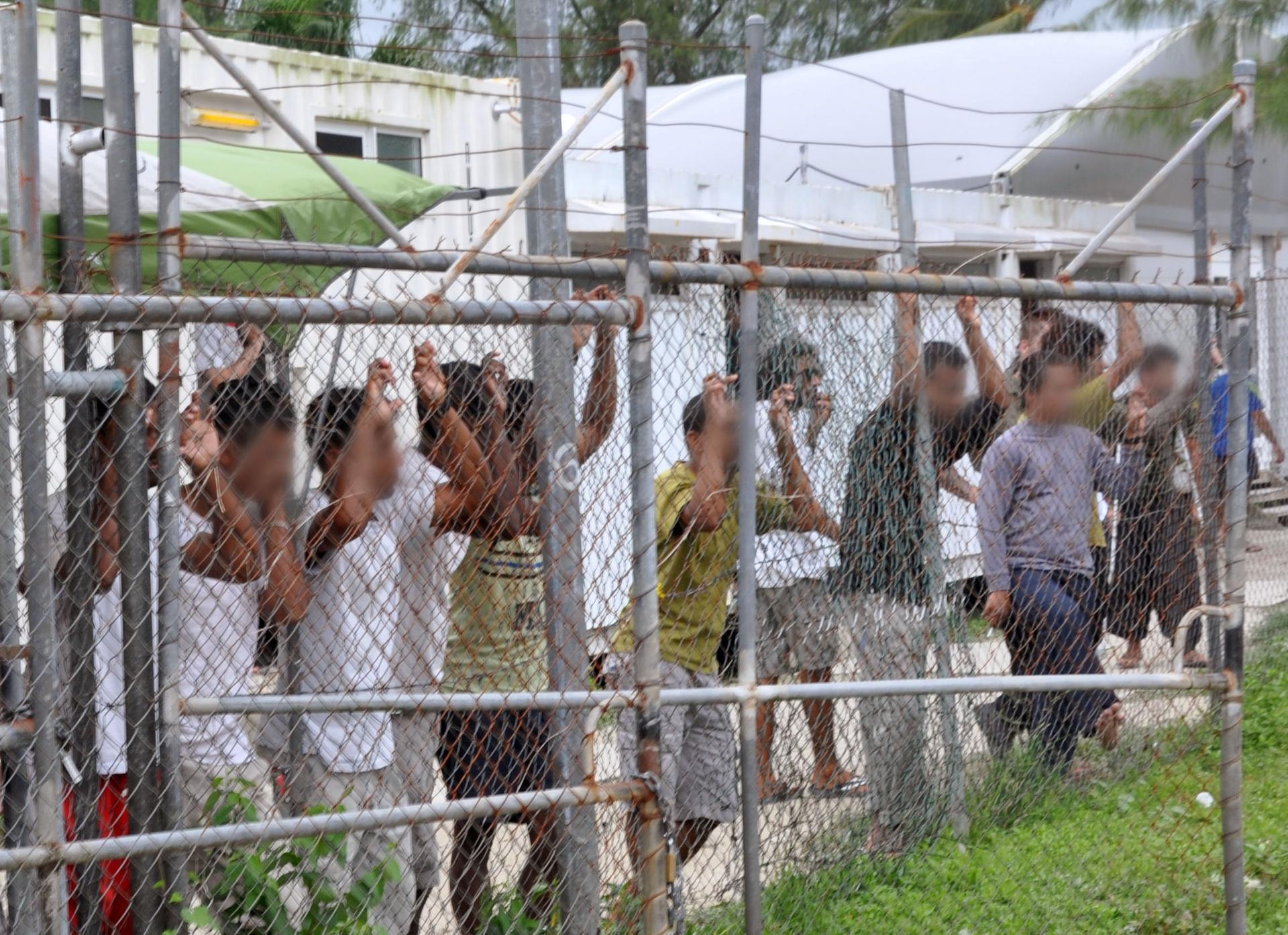 Asylum-seekers look through a fence at the Manus Island detention center in Papua New Guinea March 21, 2014. It is scheduled to close October 31, 2017. Eoin Blackwell/AAP/via Reuters/File Photo ATTENTION EDITORS - FACES PIXELLATED AT SOURCE. THIS PICTURE 