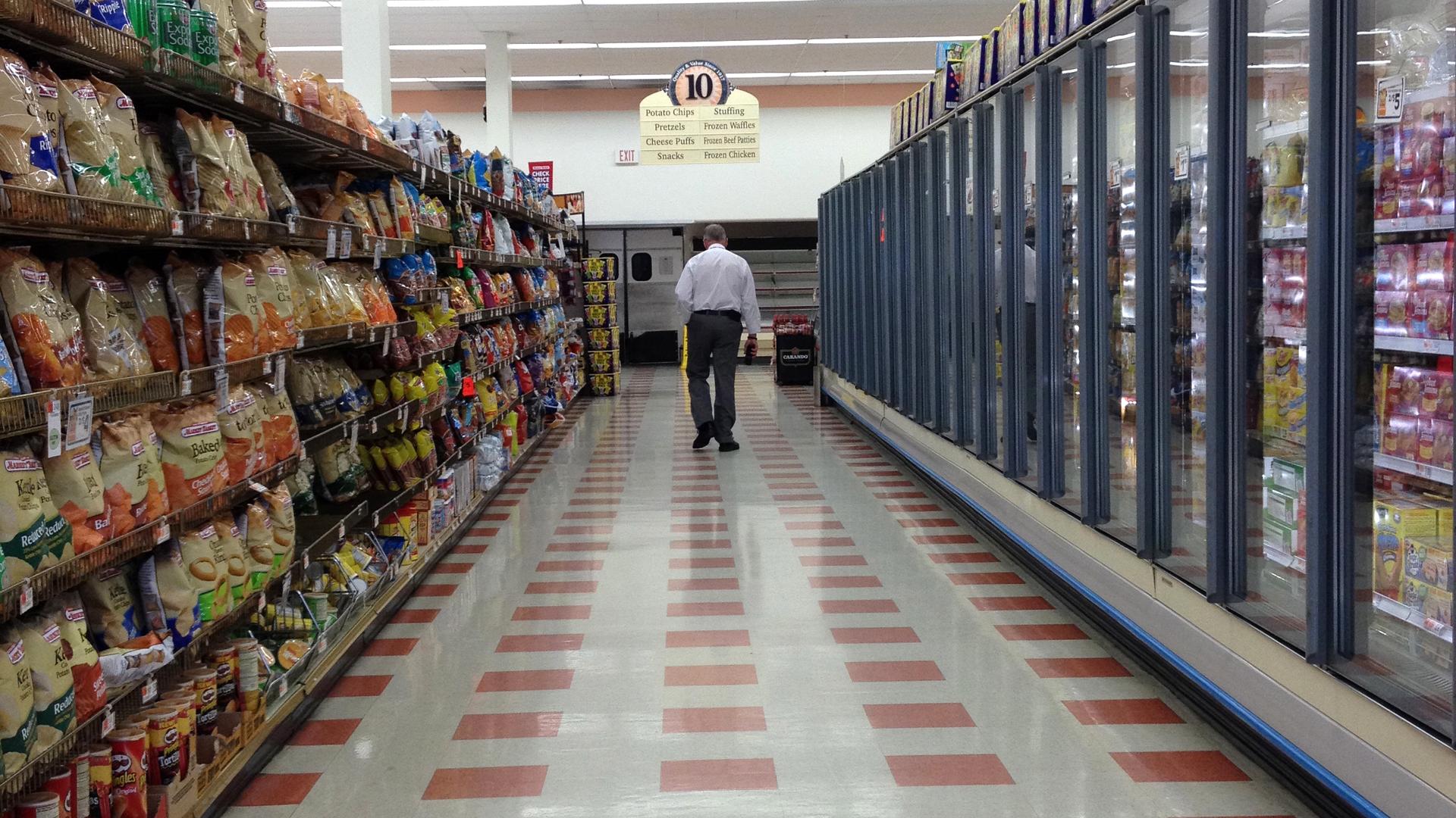 Michael Dunleavy walks down an empty aisle of the Market Basket grocery store he manages in Somerville, Mass.