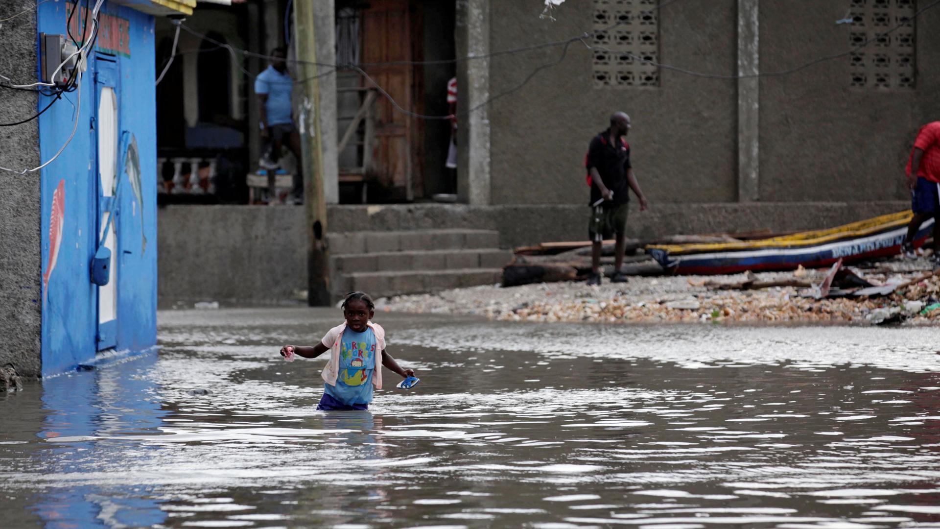 A girl trudges through a flooded area after Hurricane Matthew in Les Cayes, Haiti.
