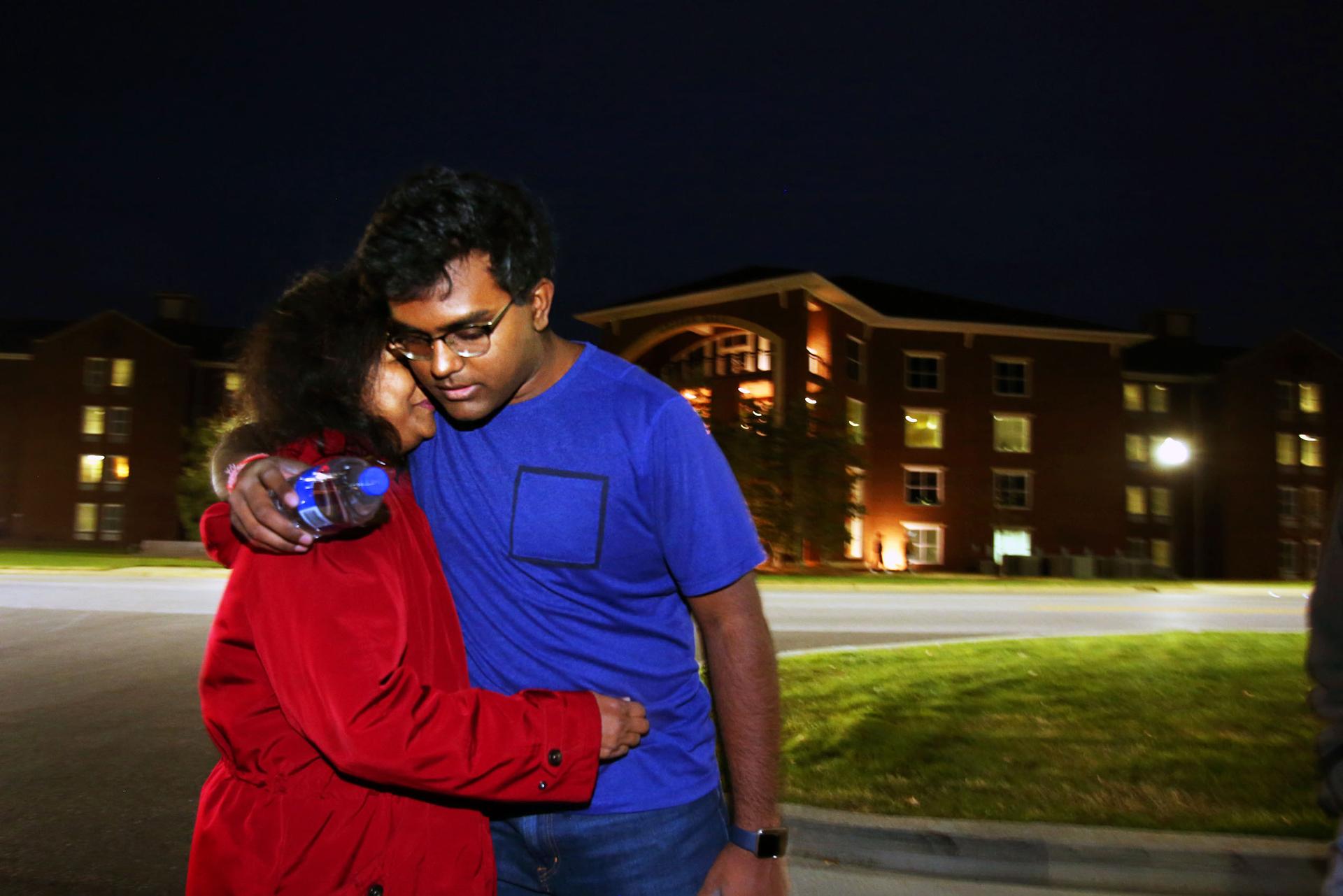 Woman hugs man in evening scene in front of building