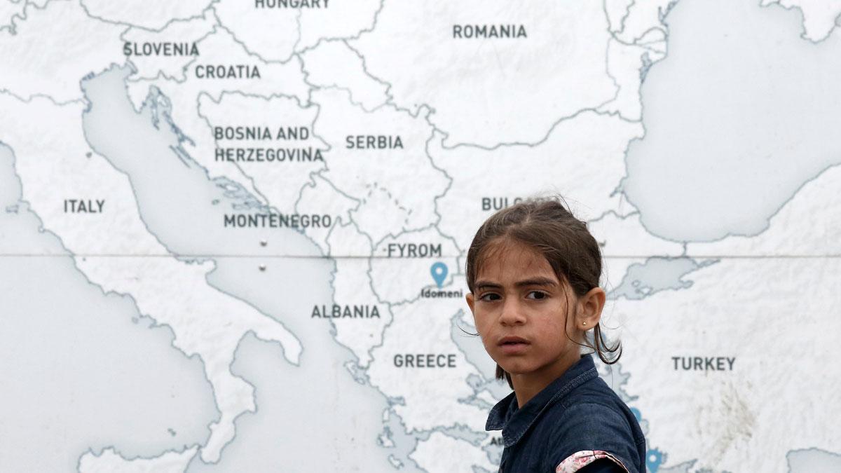 A girl walks past a map illustrating part of Europe, at a makeshift camp for refugees and migrants at the Greek-Macedonian border in Greece.