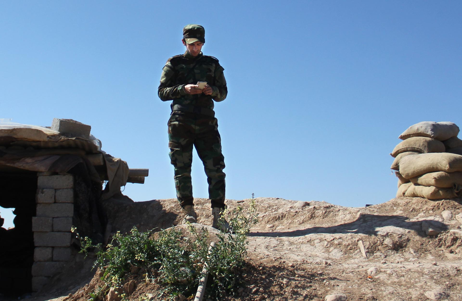 A Kurdish-Iraqi fighter checking his smart photo on the frontline outside Erbil, in Kurdistan.