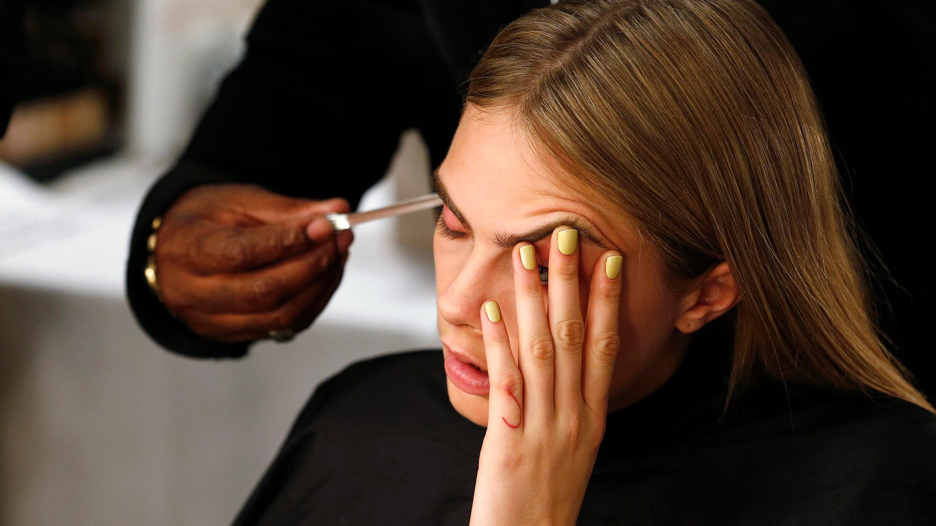 Model Cara Delevingne has her hair styled backstage during London Fashion Week.