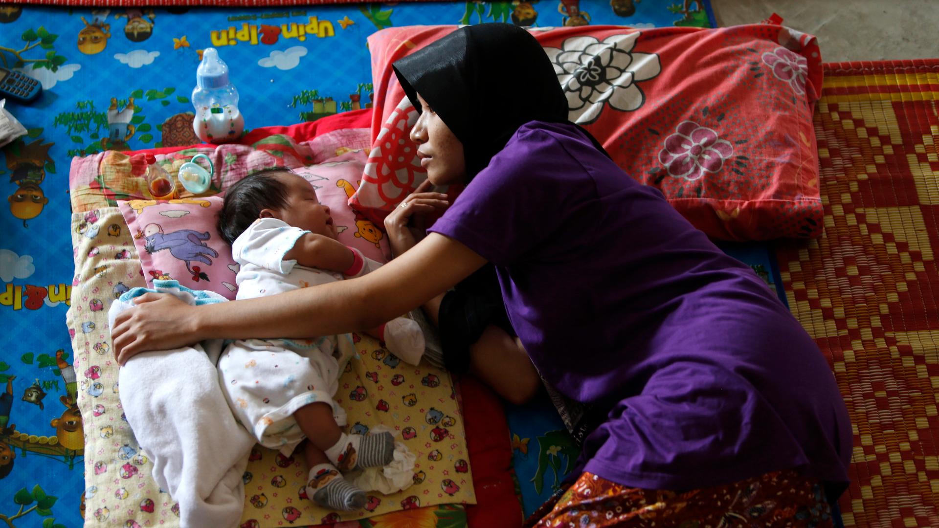A woman rests next to her baby outside Kuala Lumpur.