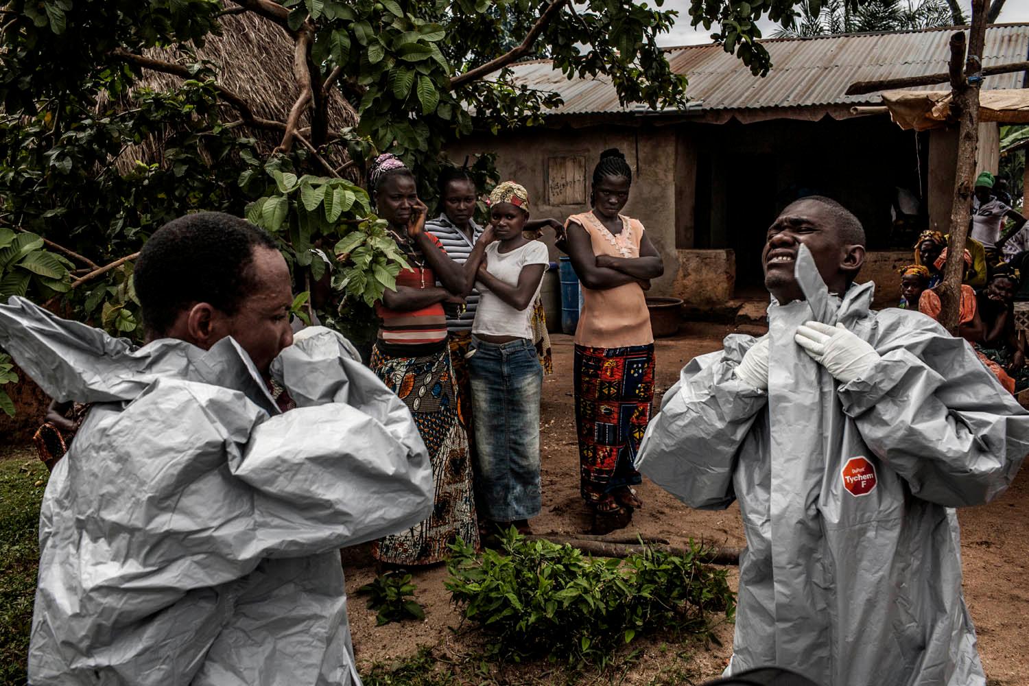 Members of a Red Cross burial team put on personal protective equipment before entering the home of a woman suspected of dying of Ebola in the village of Dia on Monday, August 18, 2014.