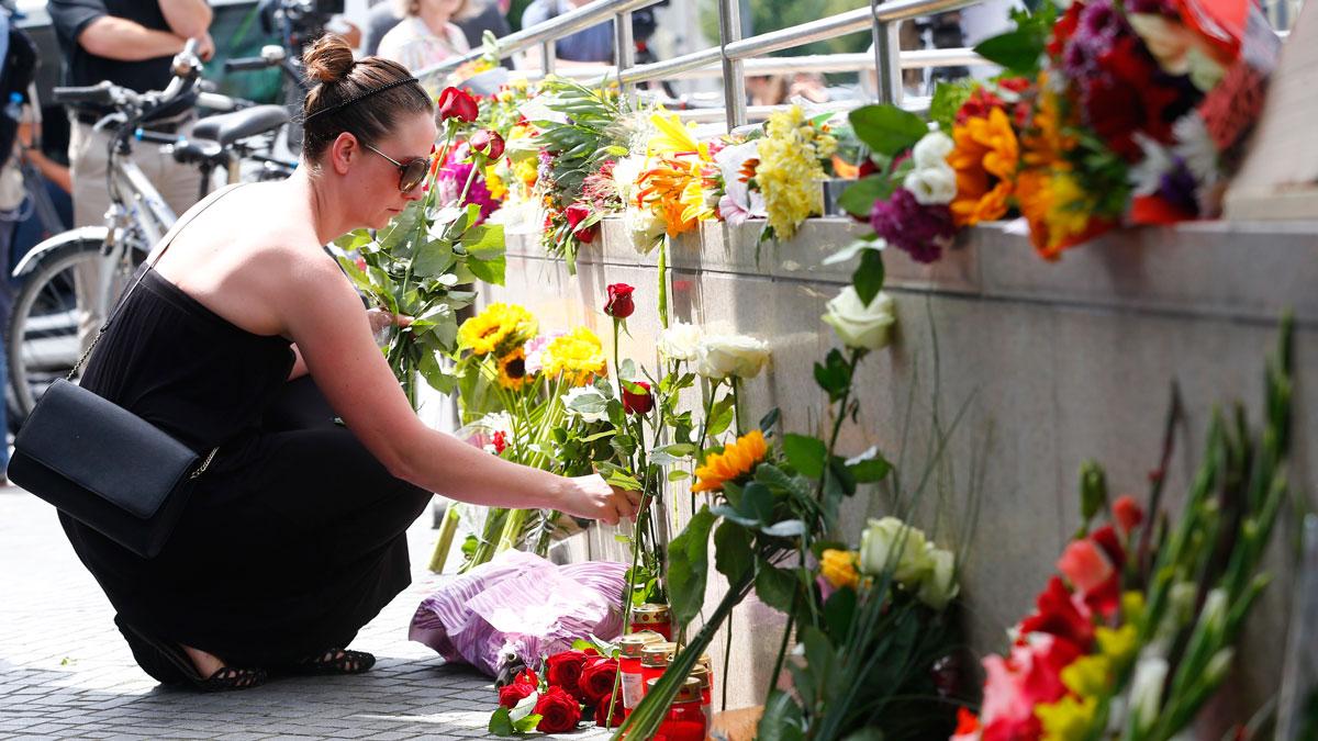 A women places flowers near the Olympia shopping mall, where Friday's shooting rampage started, in Munich.