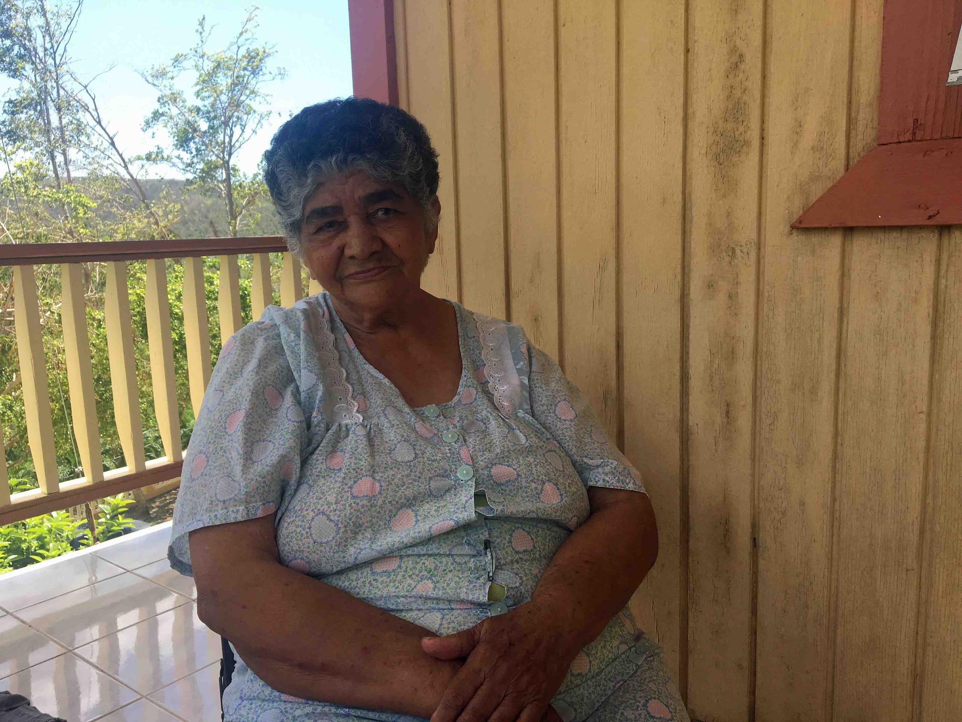 An elderly woman sitting on a porch.