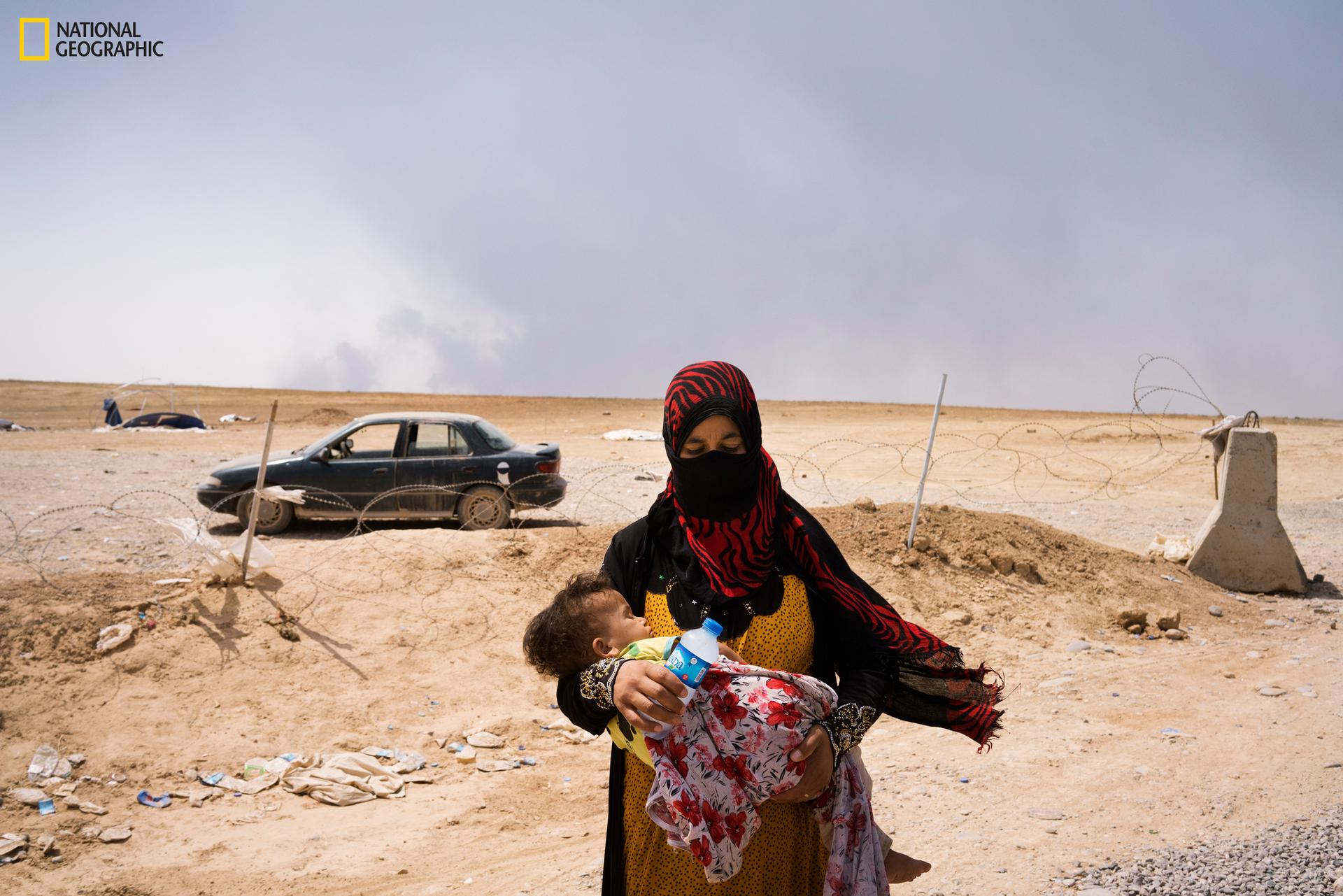 A woman and her child, having fled Qayyarah, arrive at a front line position.