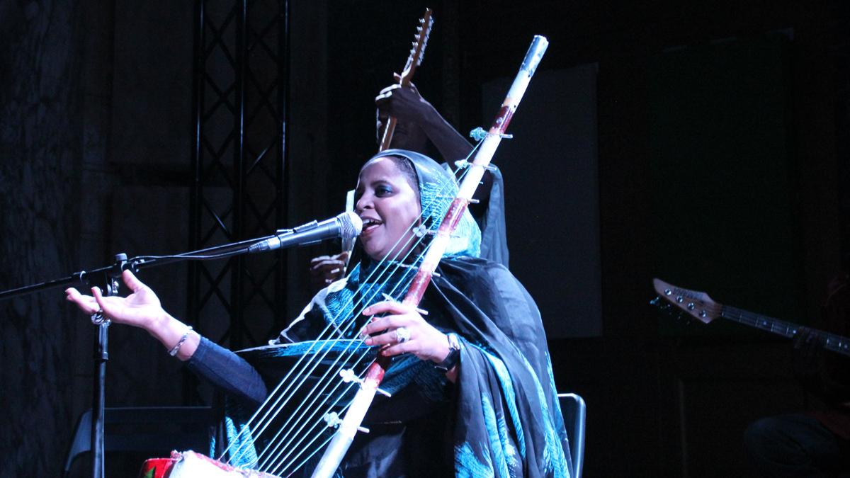 Noura Mint Seymali, with her husband Jeiche Ould Chighaly behind her, playing at the Issue Project Room in Brooklyn on her first US tour. 
