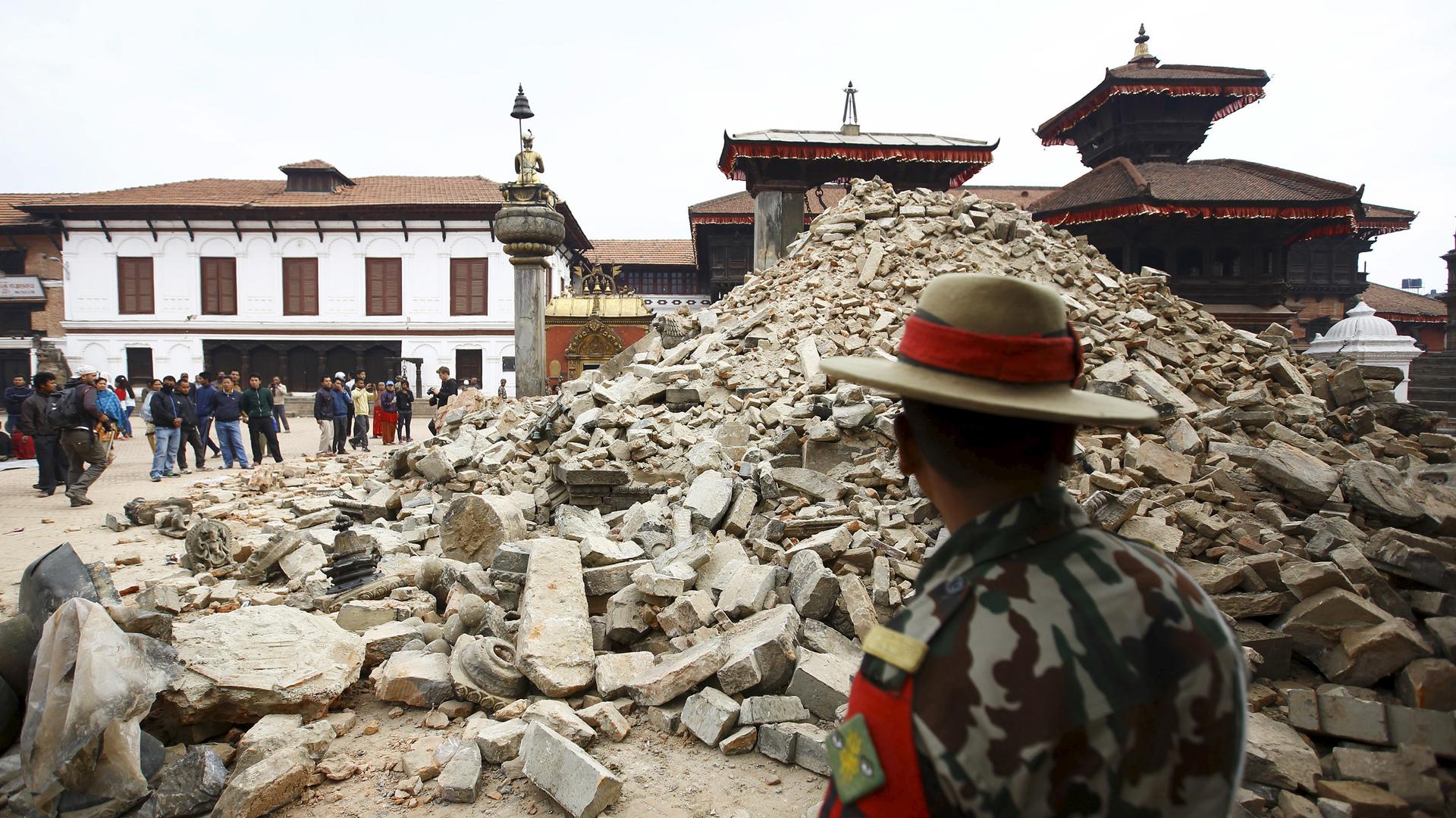 A Nepalese army personnel stands in front of a collapsed temple in Bhaktapur, Nepal a day after the April 25 earthquake rocked the country. The quake devastated the heavily crowded Kathmandu valley, killing thousands and triggering a deadly avalanche on M