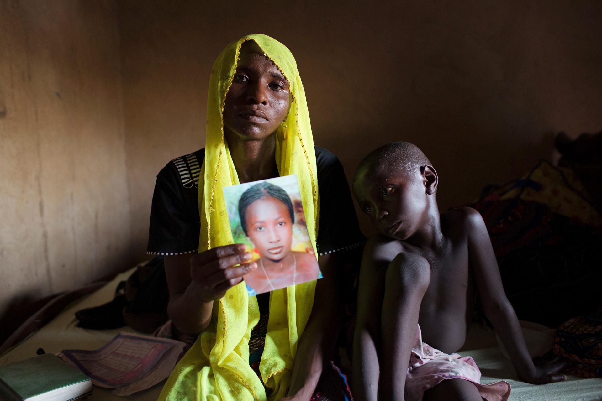 Rachel Daniel, 35, holds up a picture of her abducted daughter Rose Daniel, 17, as her son Bukar, 7, sits beside her at her home in Maiduguri in northeast Nigeria on May 21, 2014. Rose is one of the more than 200 of her classmates on April 14 by Boko Hara