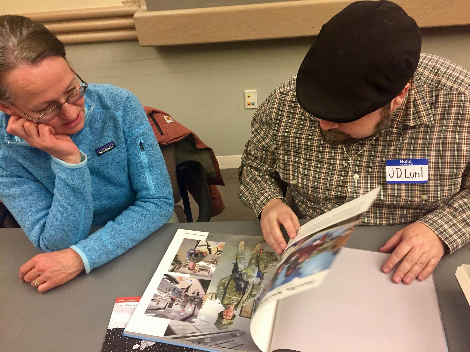 Veteran Sarah Nolin shows cartoonist J.D. Lunt her photo album of her deployment to Afghanistan.