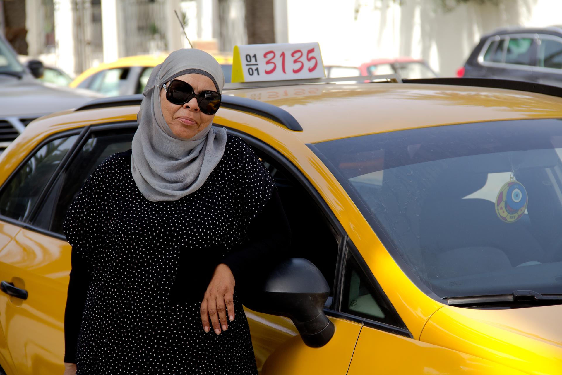 Yamina Jaouani in front of the cab that her daughter helped her buy. She's been driving a taxi in Tunis for nearly 30 years.