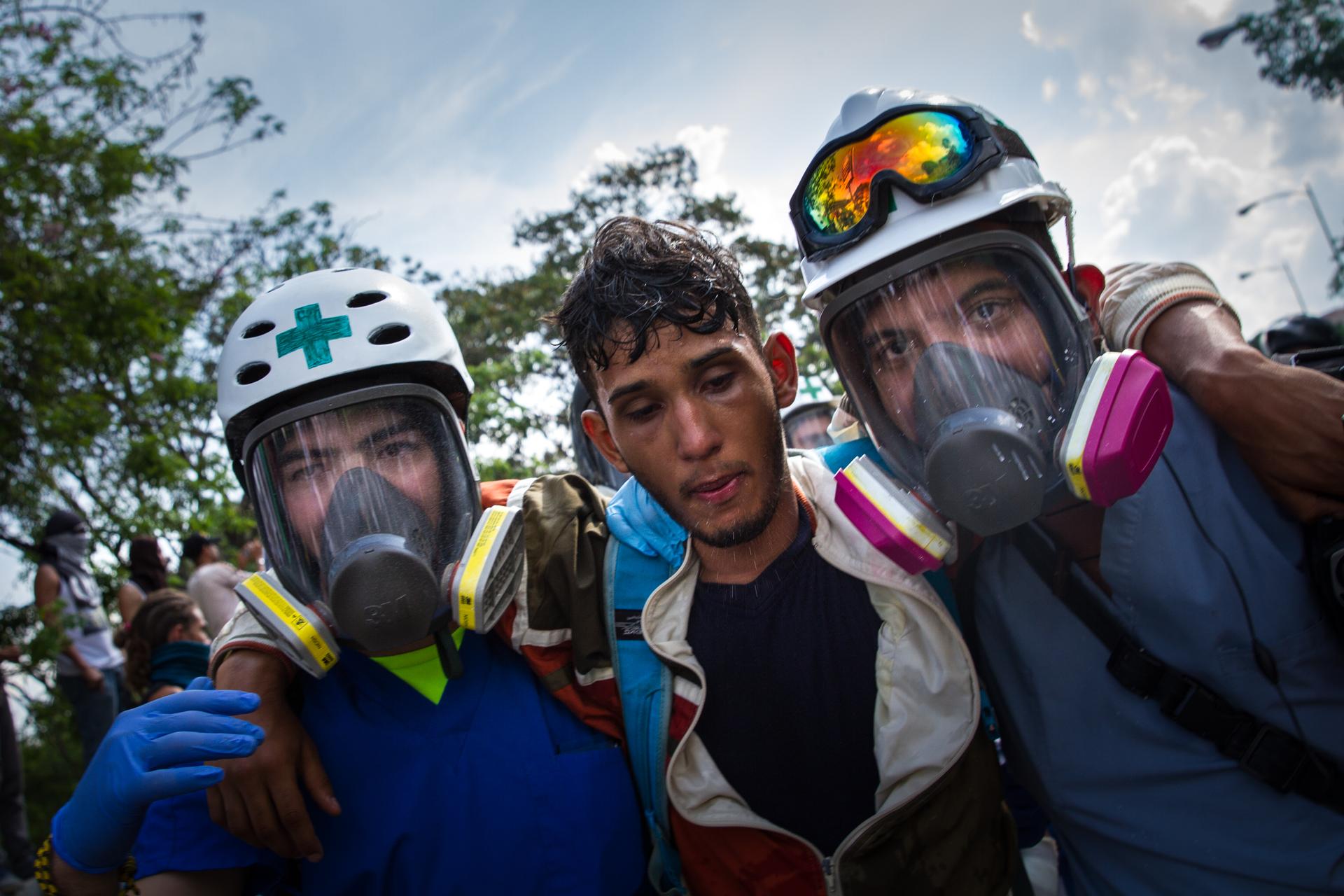 In Venezuela, two volunteers help a protester overcome by tear gas. The volunteers are mostly medical students who provide first aid at the anti-government demonstrations.
