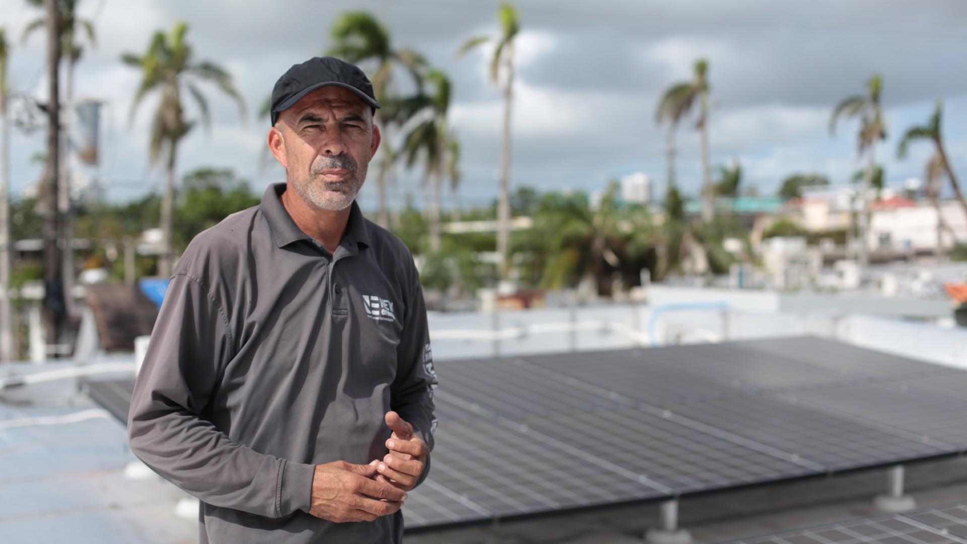Technician Alexis Portalatin stands next to rooftop solar panels he is connecting to a new Tesla battery storage system the San Juan suburb of Guaynabo. The storage system will allow the panels to operate separately from the power grid and supply electric