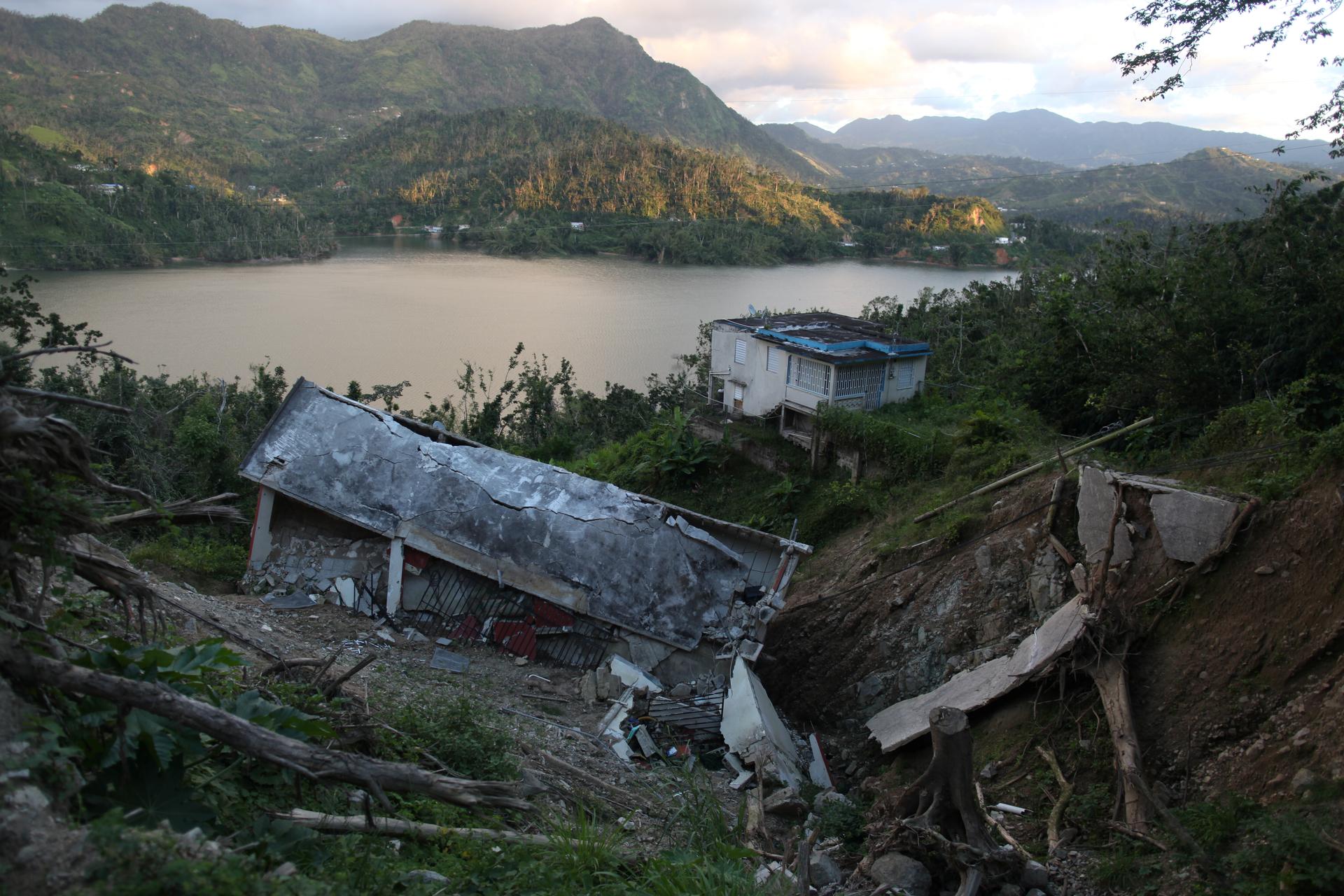 collapsed house in ravine with lake and mountains in background