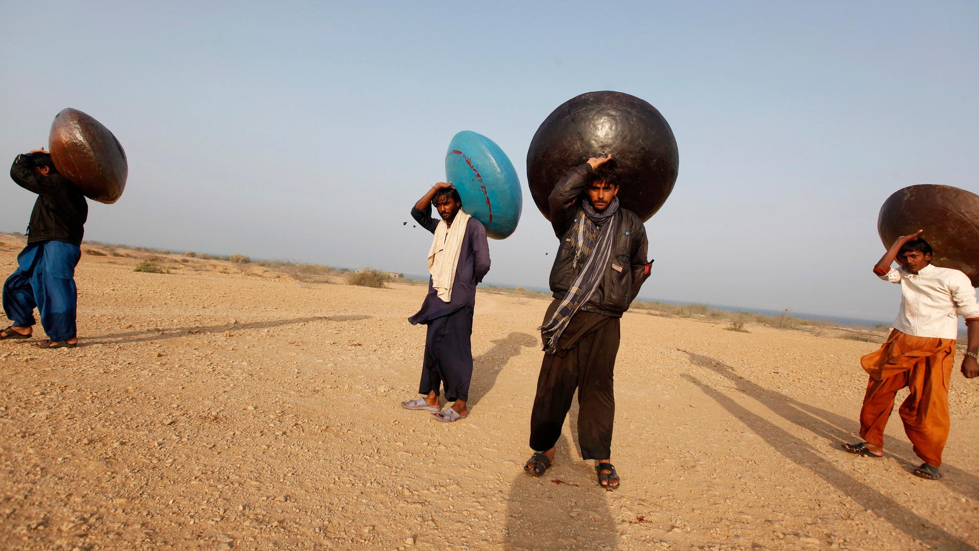 Men carry floating pitchers which they use to catch fish while heading home in Soneri village next to Keenjhar Lake, near Thatta, Pakistan.