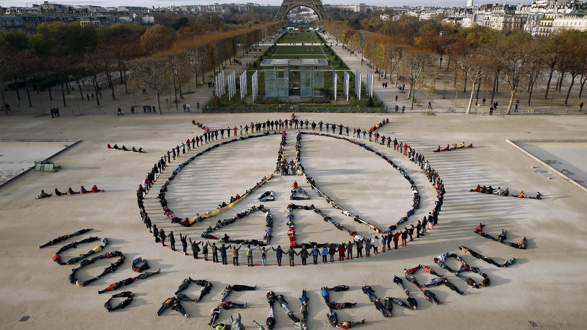 Hundreds of environmentalists arrange their bodies to form a message in front of the Eiffel Tower in Paris, France, December 6, 2015, as the World Climate Change Conference 2015 (COP21) continues at Le Bourget near the French capital.