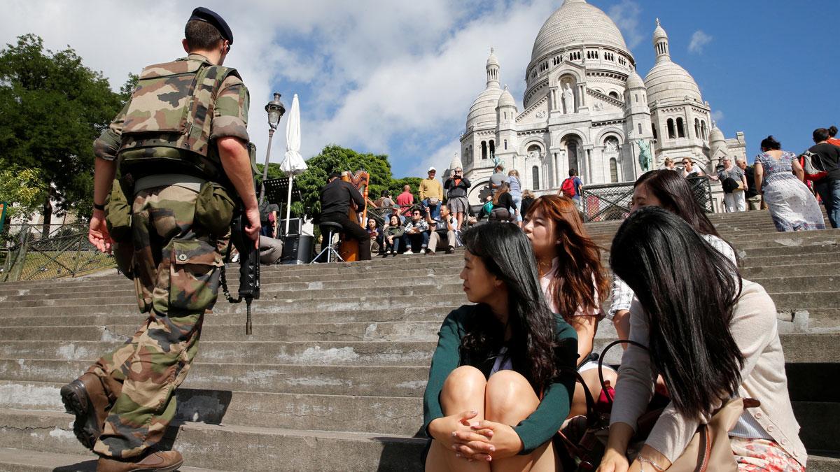 A French soldier patrols under the gaze of Korean tourists at Montmartre's Sacre Coeur Church in Paris.