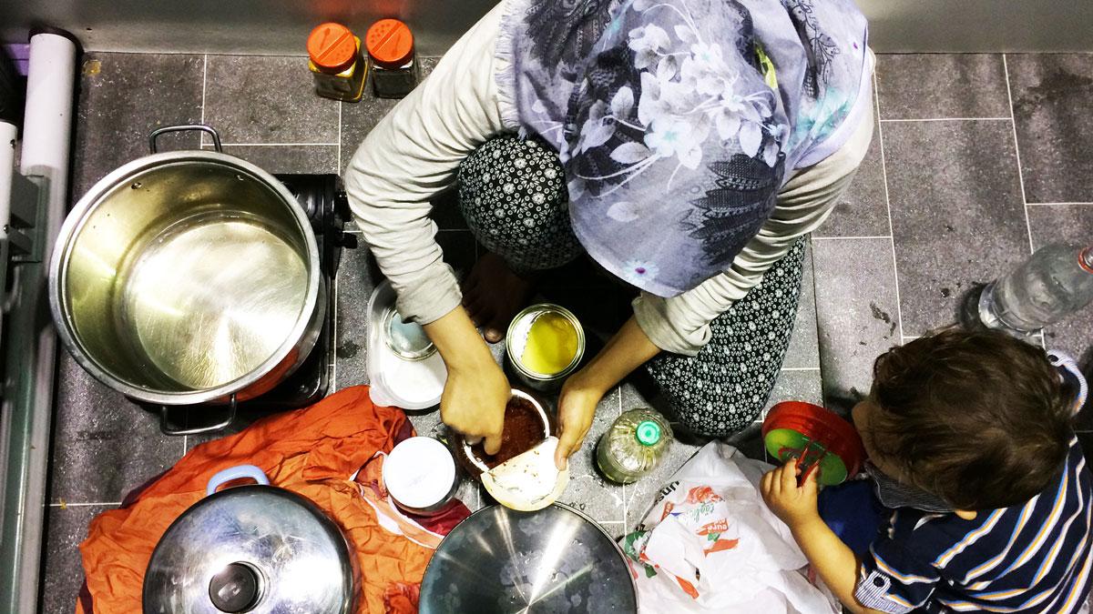 Bushra cooks food for her family inside her temporary living quarters at Berlin’s Tempelhof refugee shelter.