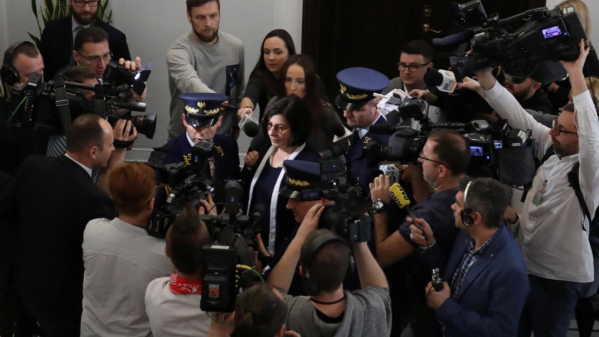 Israel's Ambassador to Poland, Anna Azari, is surrounded by photographers and security officials.