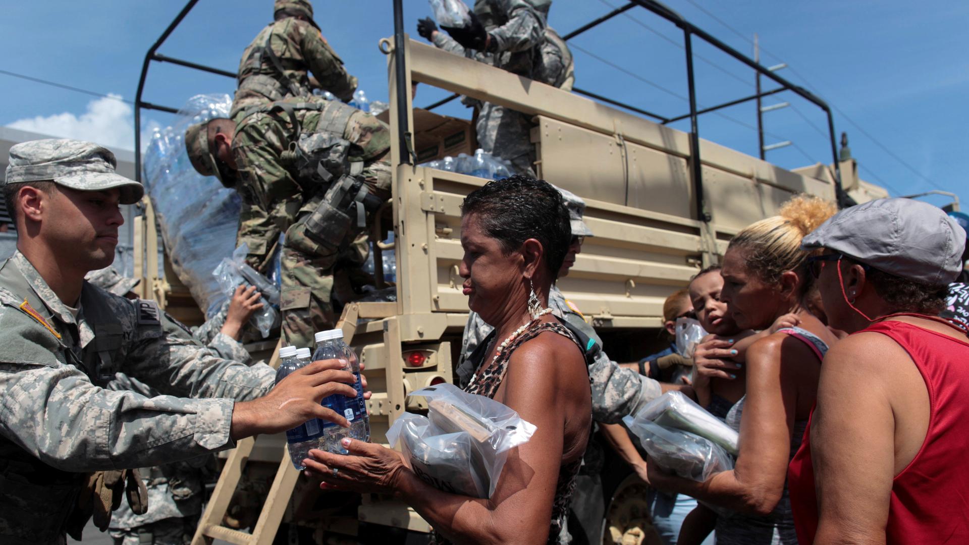 Soldiers of Puerto Rico's national guard distribute relief items to people, Sept. 24, 2017, after the area was hit by Hurricane Maria in San Juan, Puerto Rico.