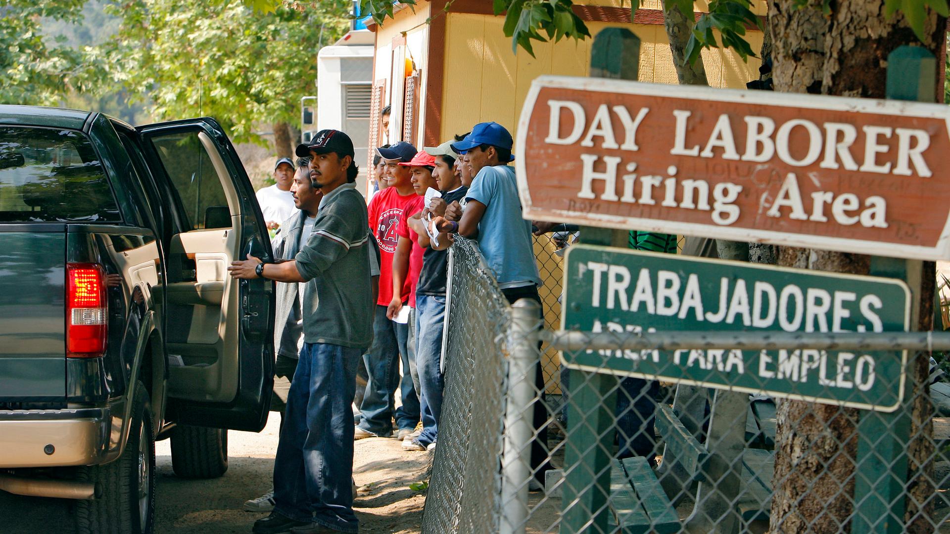 Day laborers enter a truck after being chosen by an employer at a hiring area in Laguna Beach, California
