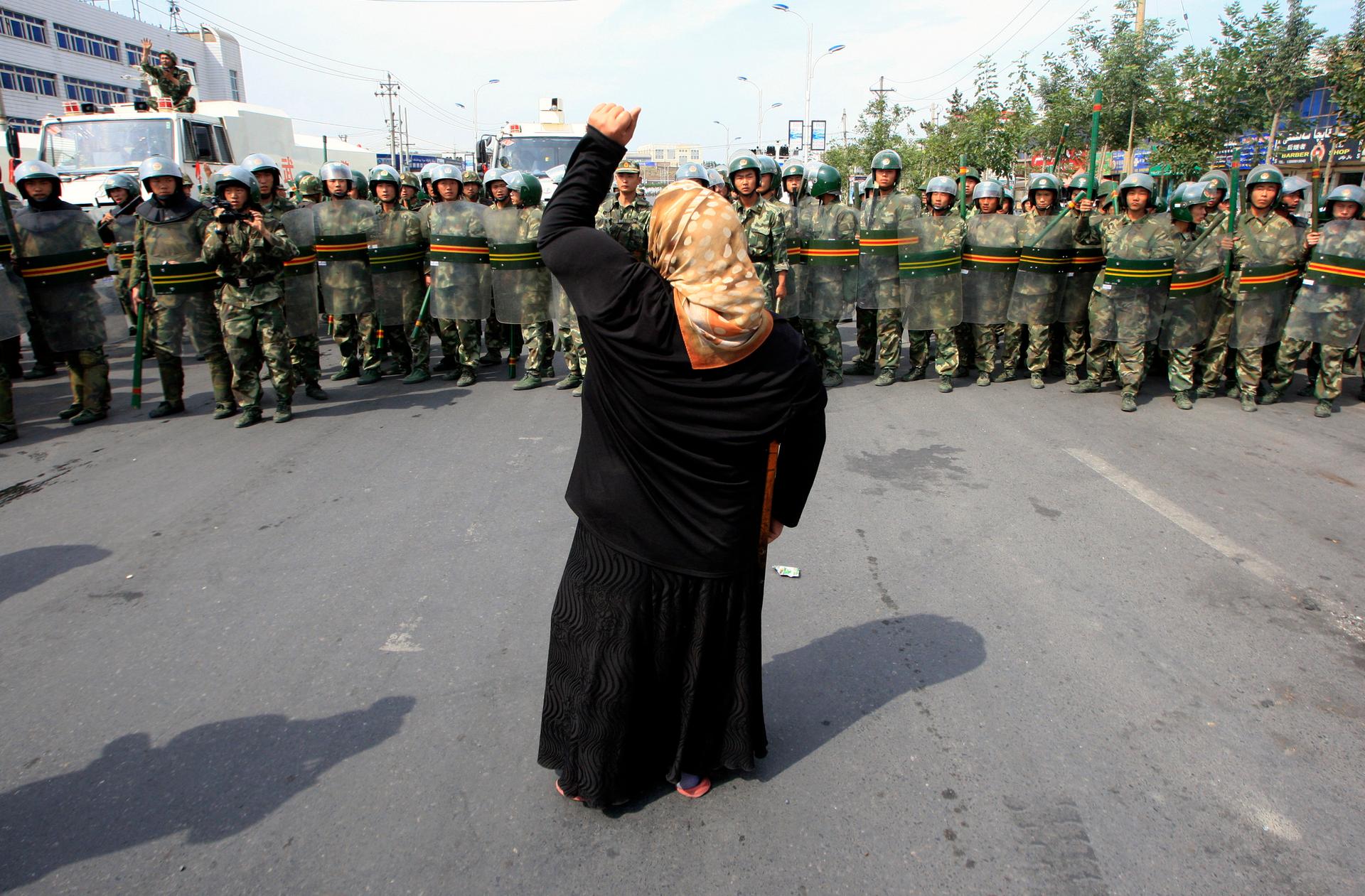 A local woman on a crutch shouts at Chinese paramilitary police as a crowd of angry locals confront security forces on a street in the city of Urumqi in China's Xinjiang Autonomous Region in 2009.