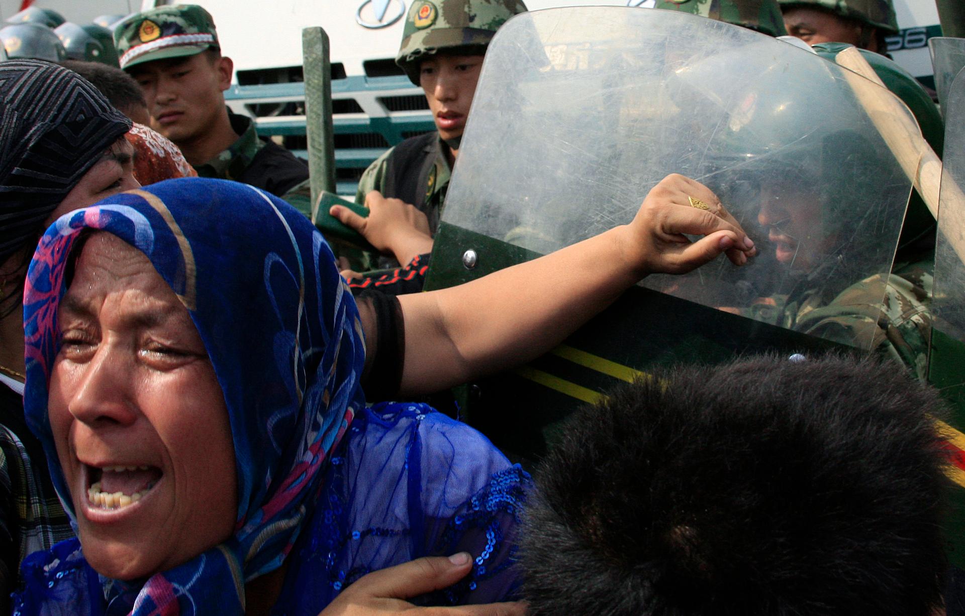 A woman pushes at Chinese paramilitary police wearing riot gear as a crowd of angry locals confront security forces on a street in the city of Urumqi in China's Xinjiang Autonomous Region on July 7, 2009.