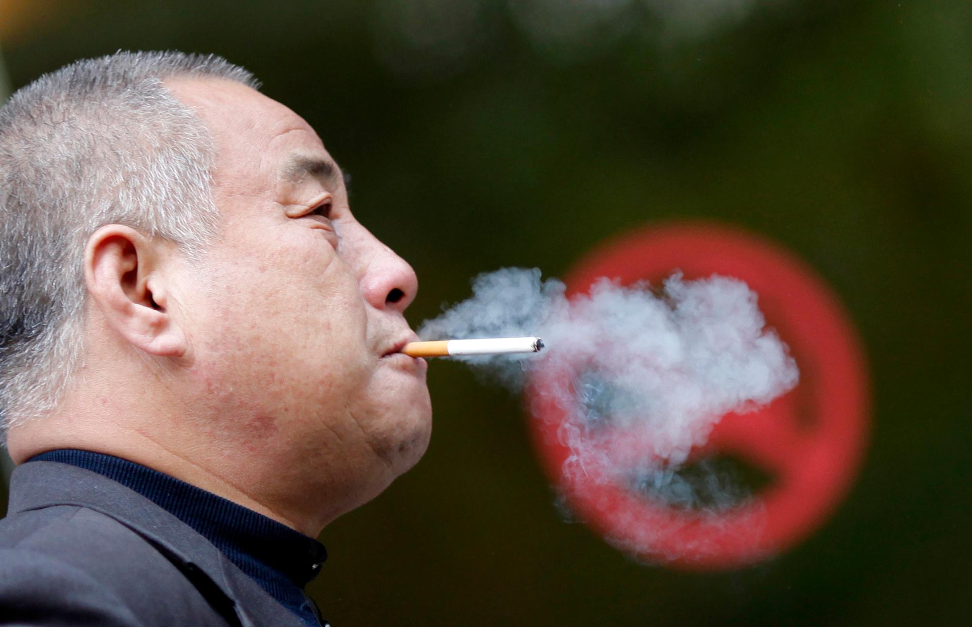 A man smokes next to a "No Smoking" sign in downtown Shanghai. Chinese leaders are now banned from smoking in public.
