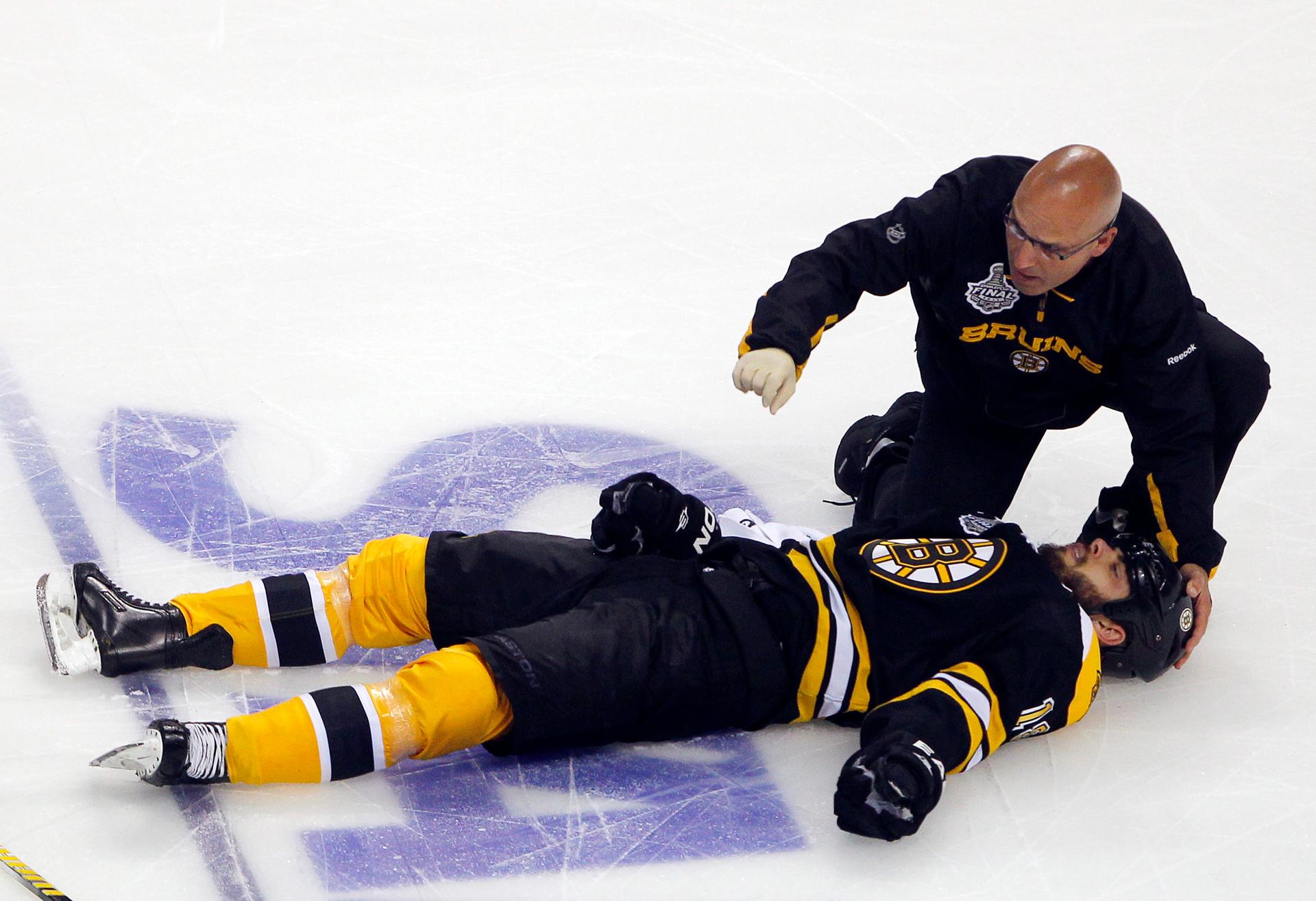 A trainer kneels over the Boston Bruins' Nathan Horton after Horton was hit by the Vancouver Canucks' Aaron Rome in Boston, Massachusetts, June 6, 2011.