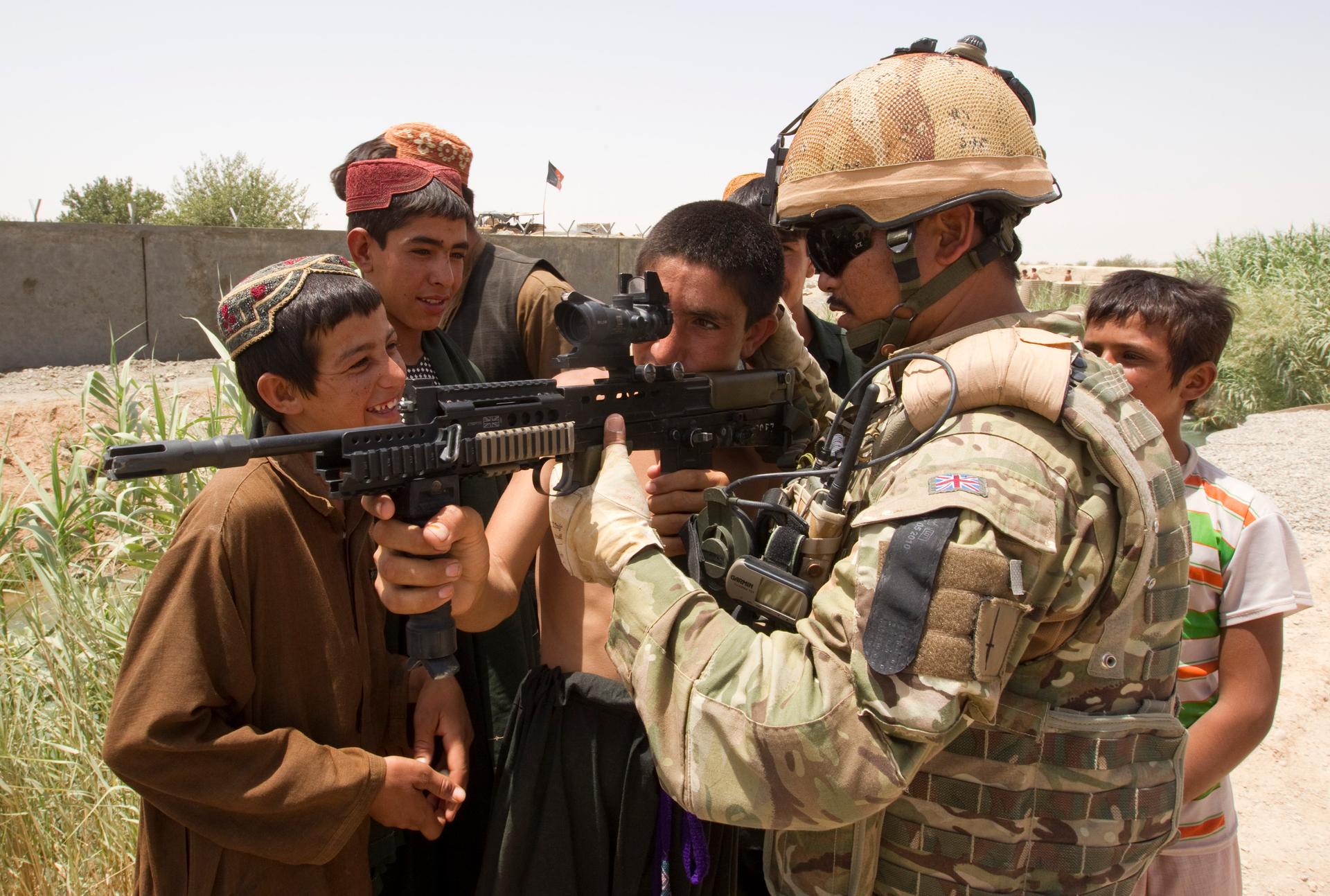 British Army Cpl. Birendra Limbu of the 2nd Battalion, The Royal Gurkha Rifles, shows his rifle to Afghan children outside the town of Lashkar Gah in Helmand province.