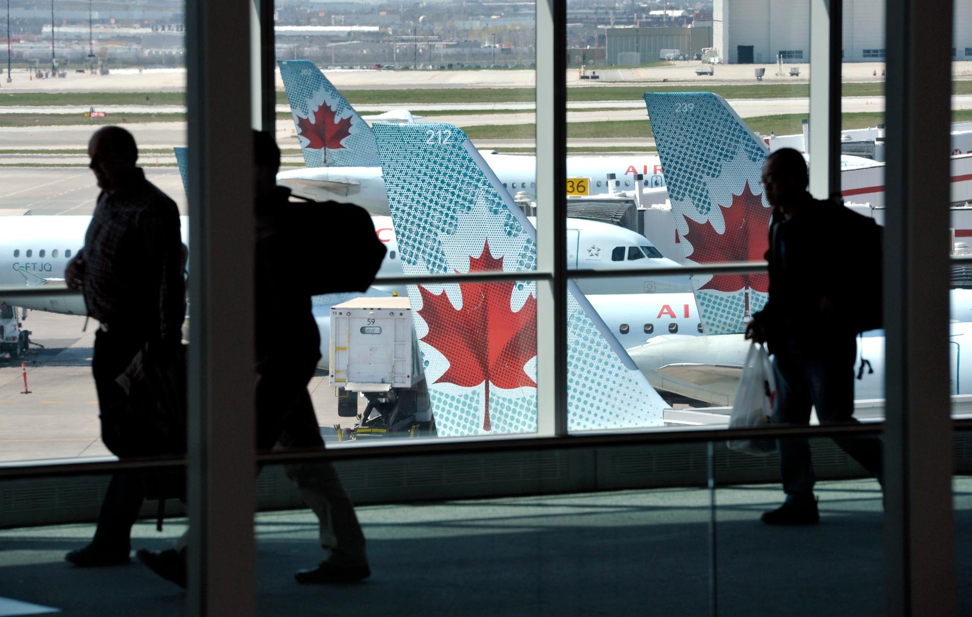 Passengers walk past Air Canada planes on the runway at Pearson International Airport in Toronto April 13, 2012.