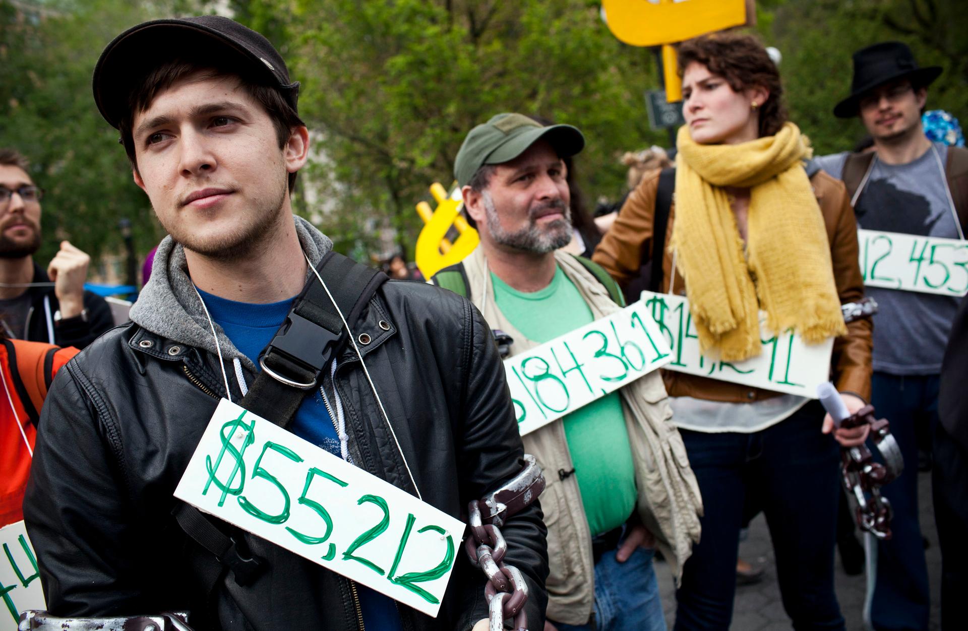 Occupy Wall Street demonstrators wear signs around their neck representing their student debt during a protest against the rising national student debt in New York on April 25, 2012.