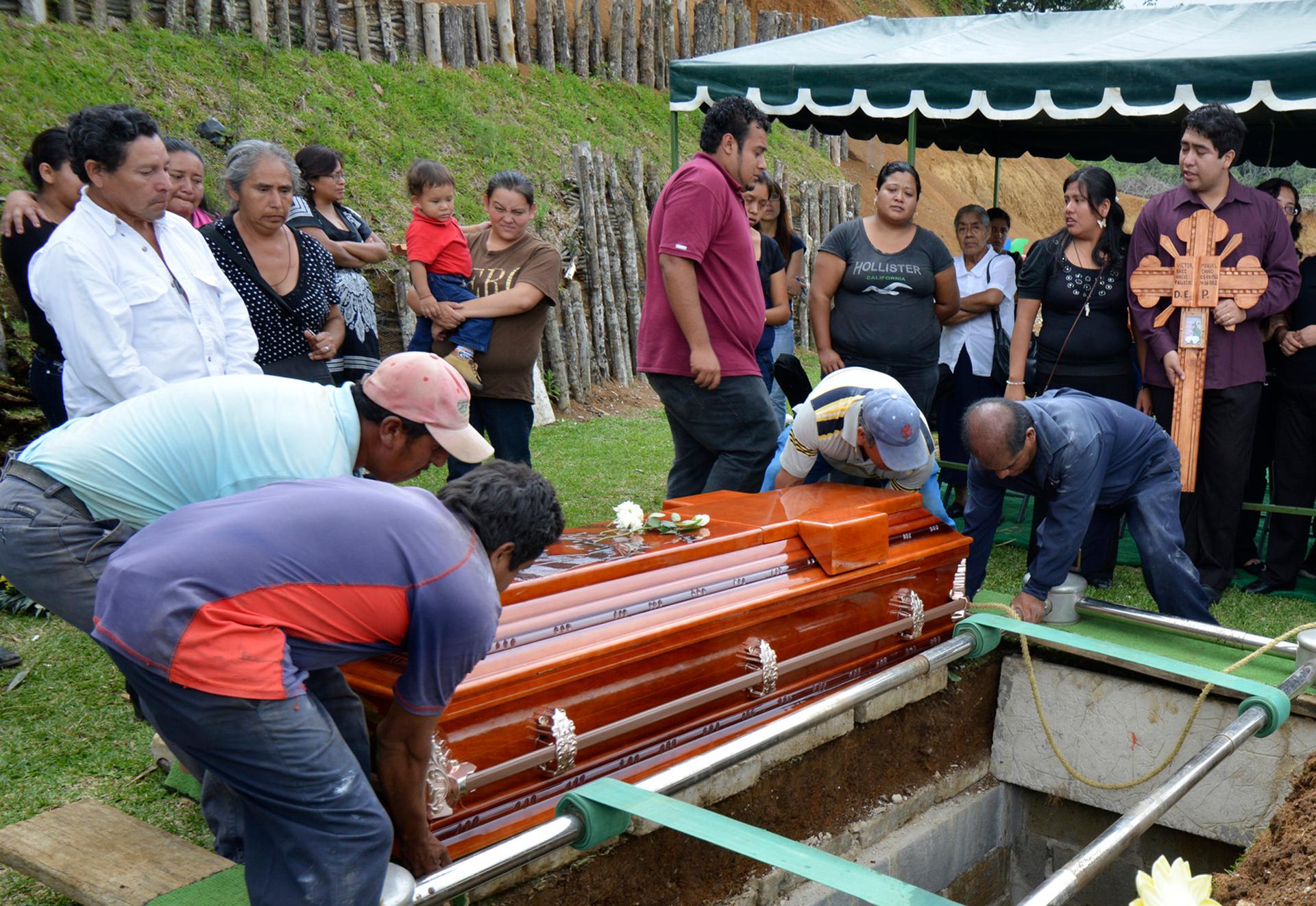 People and relatives stand next to the coffin of a murdered Mexican reporter named Victor Baez, during his funeral in Mexico's Veracruz state on June 15, 2012.