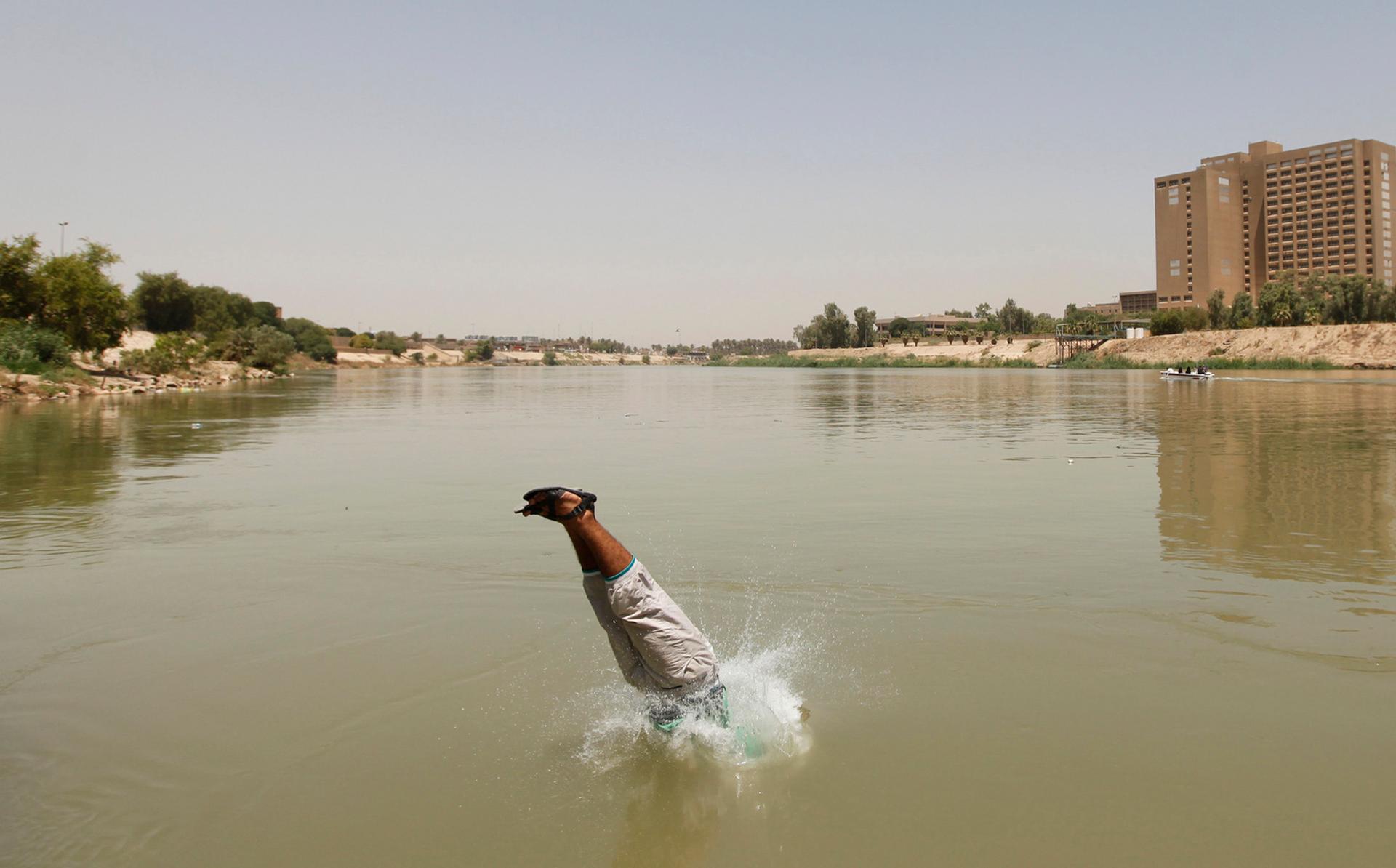 A Bagdad resident plunges into the Tigris river, sandals and all. 